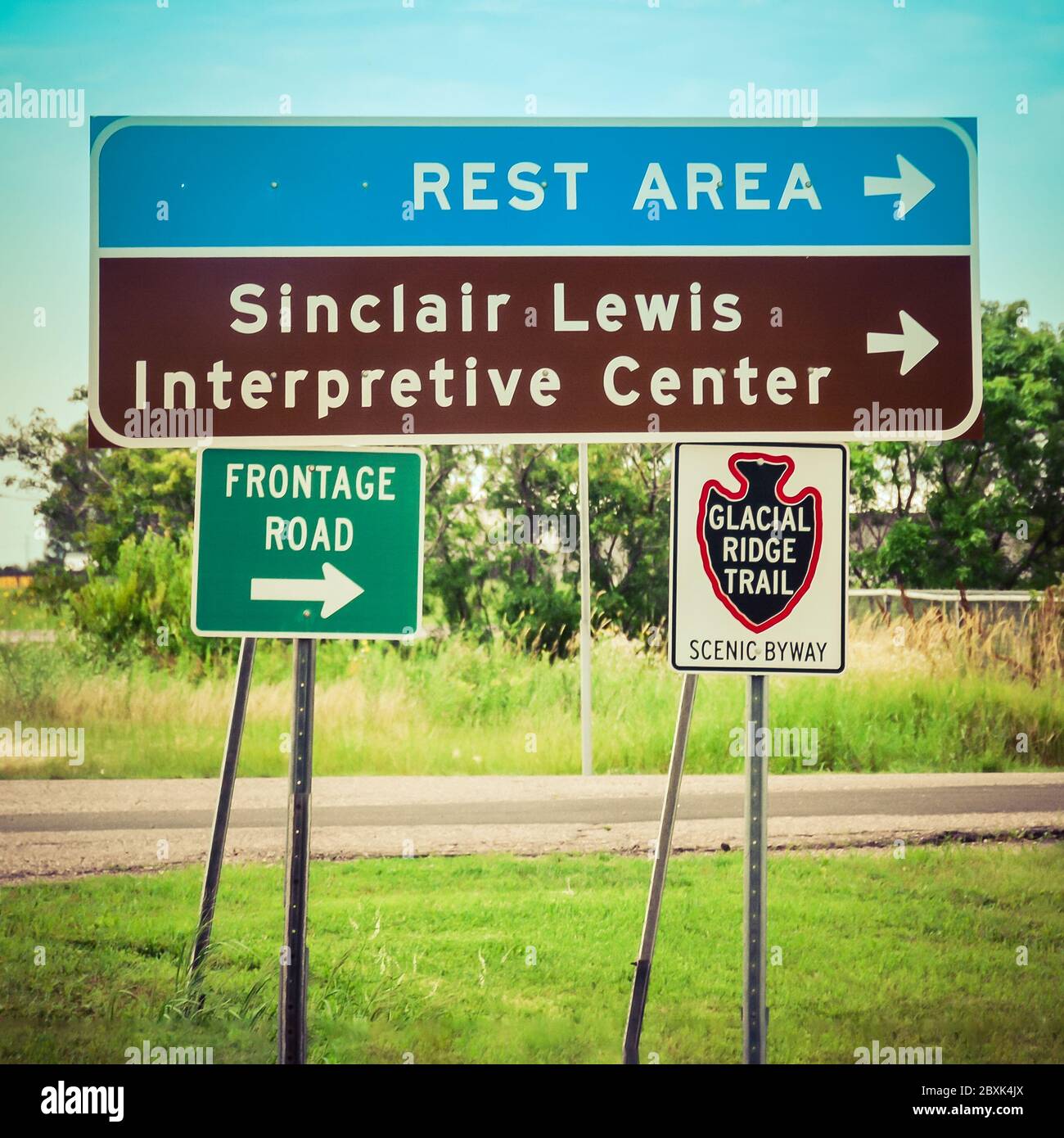 A collection of road signs for a Rest area, a frontage road, the Glacial Ridge Trail, a scenic highway and the Sinclair Lewis Interpretive Center, MN Stock Photo