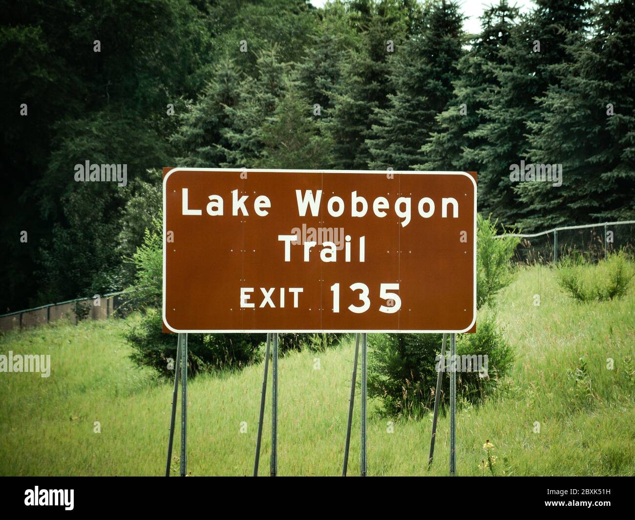 The Lake Wobegon Trail exit 135 road sign, surrounded by forest  in central Minnesota near St. Cloud on a summer's day Stock Photo