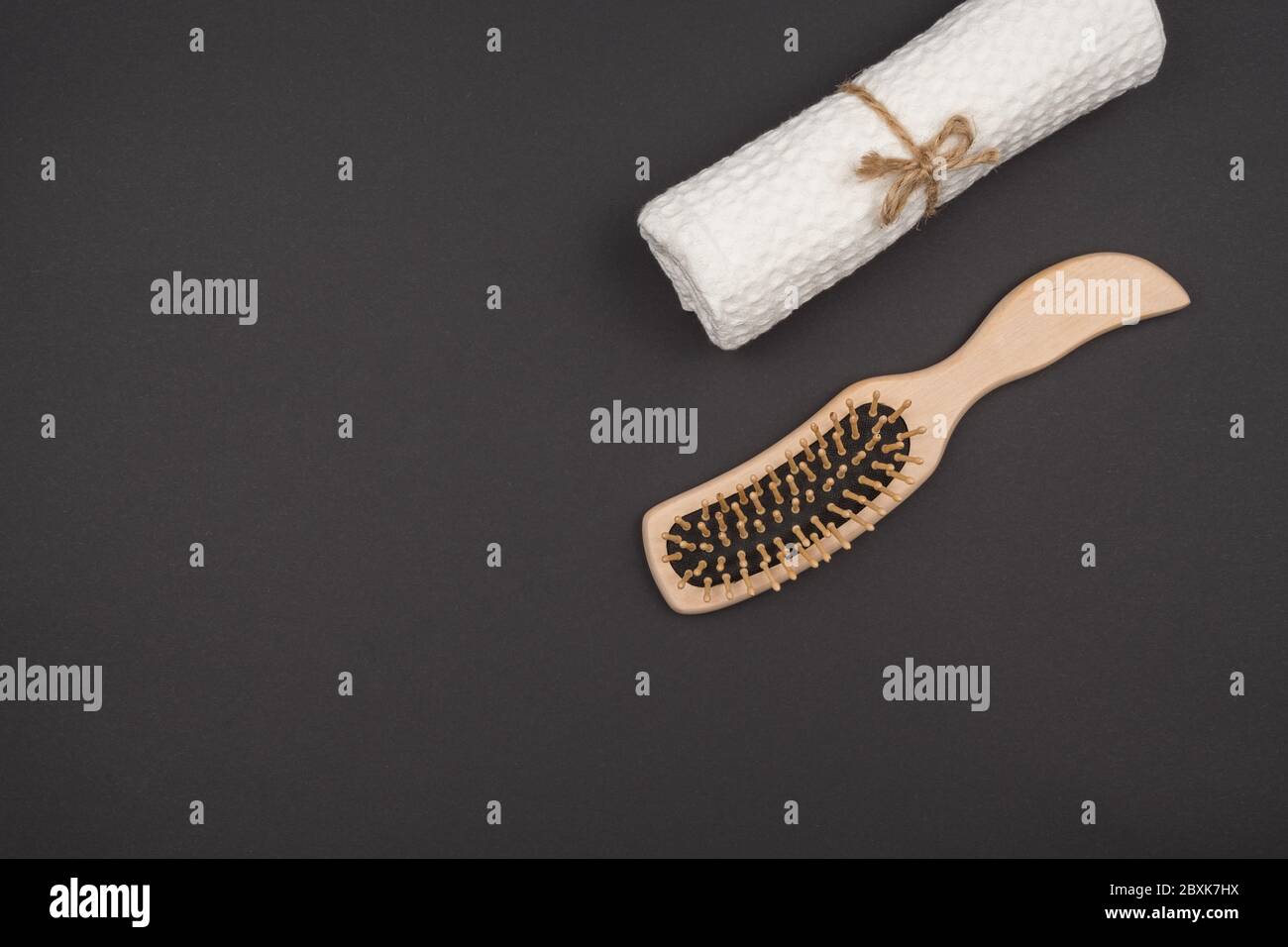 A comb and a towel roll on a black background. Stock Photo