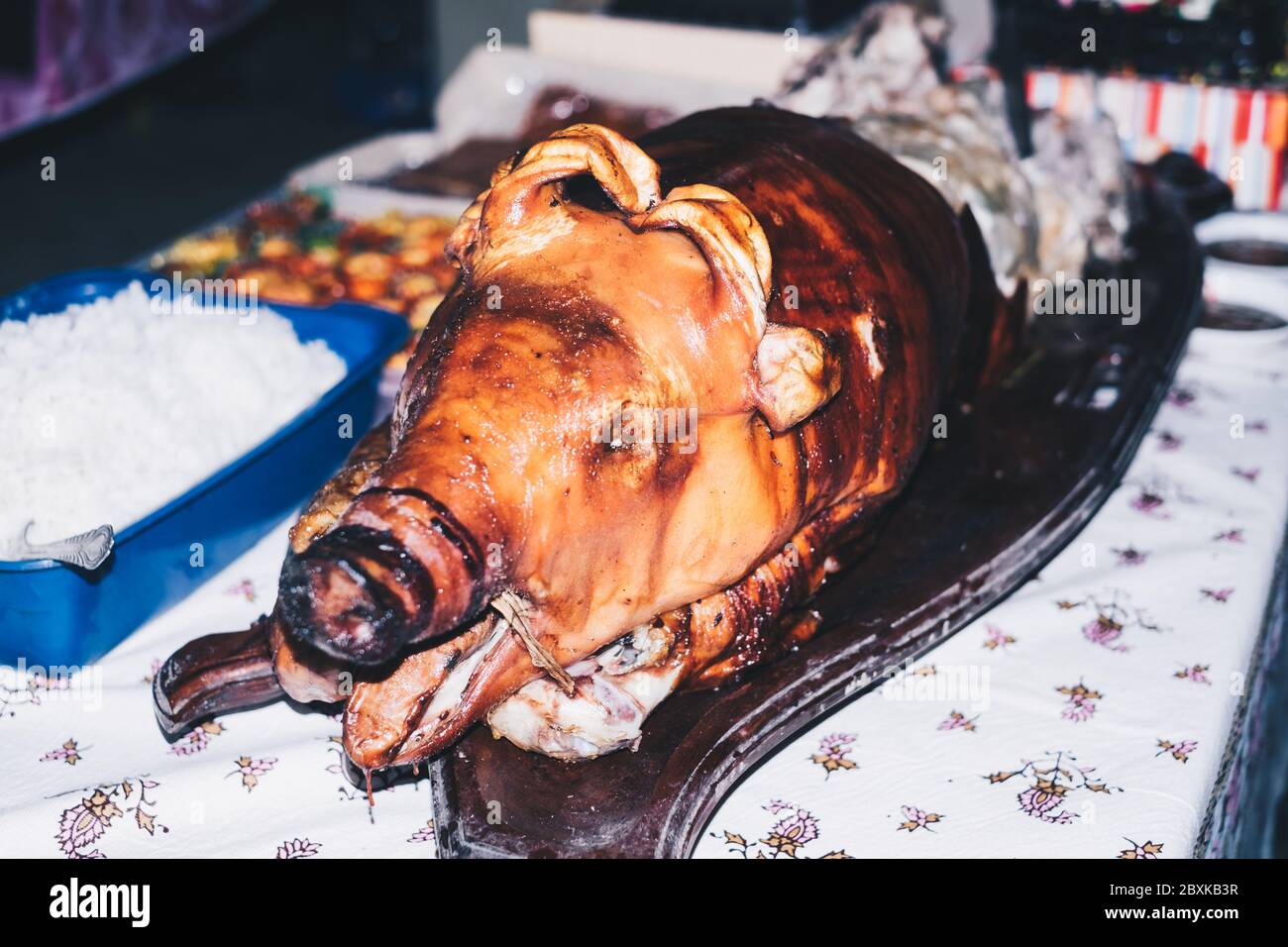 Closeup of semi-frontal view of the popular roasted pig on the table, known as 'lechon' in the Philippines, Spain, Cuba, etc. Selective focus. Stock Photo