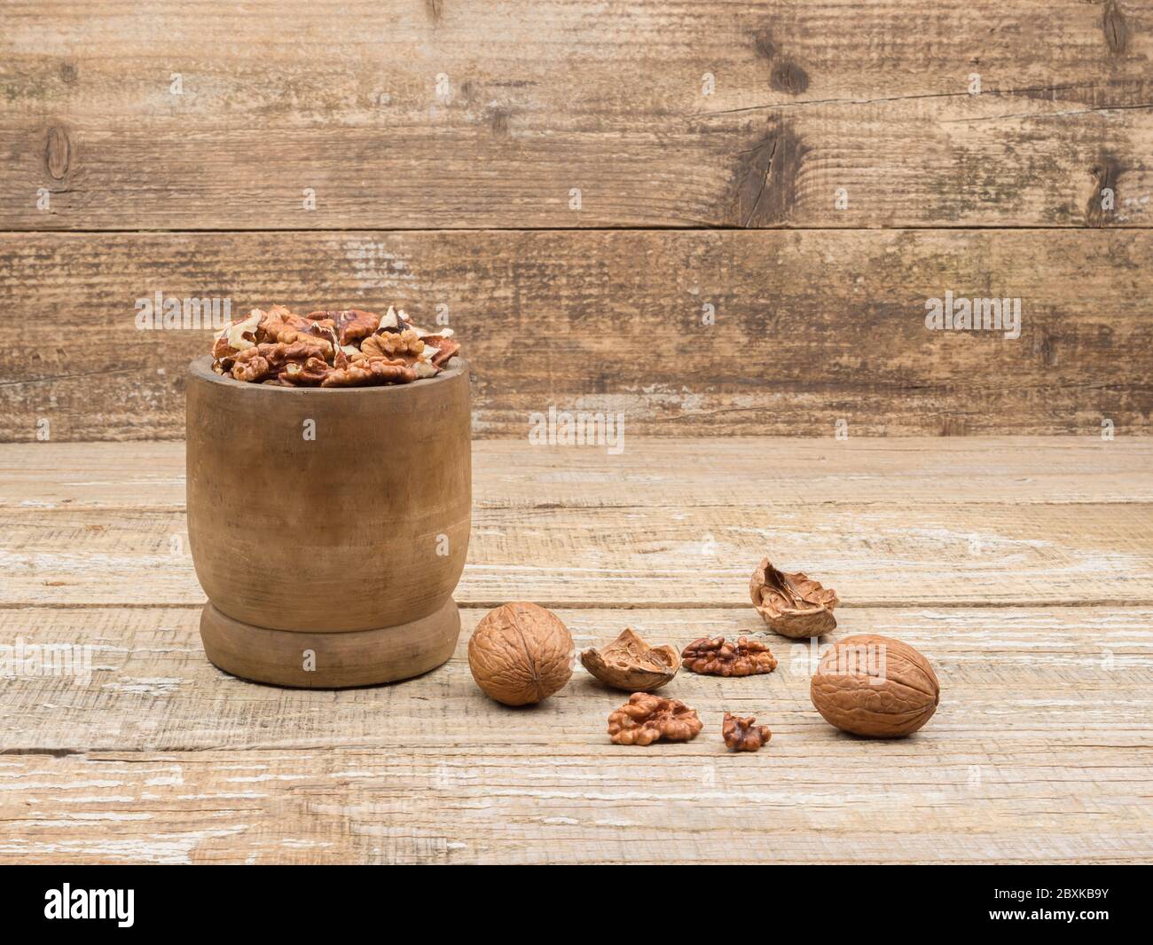 Walnuts in a wooden mortar on wooden background. Stock Photo