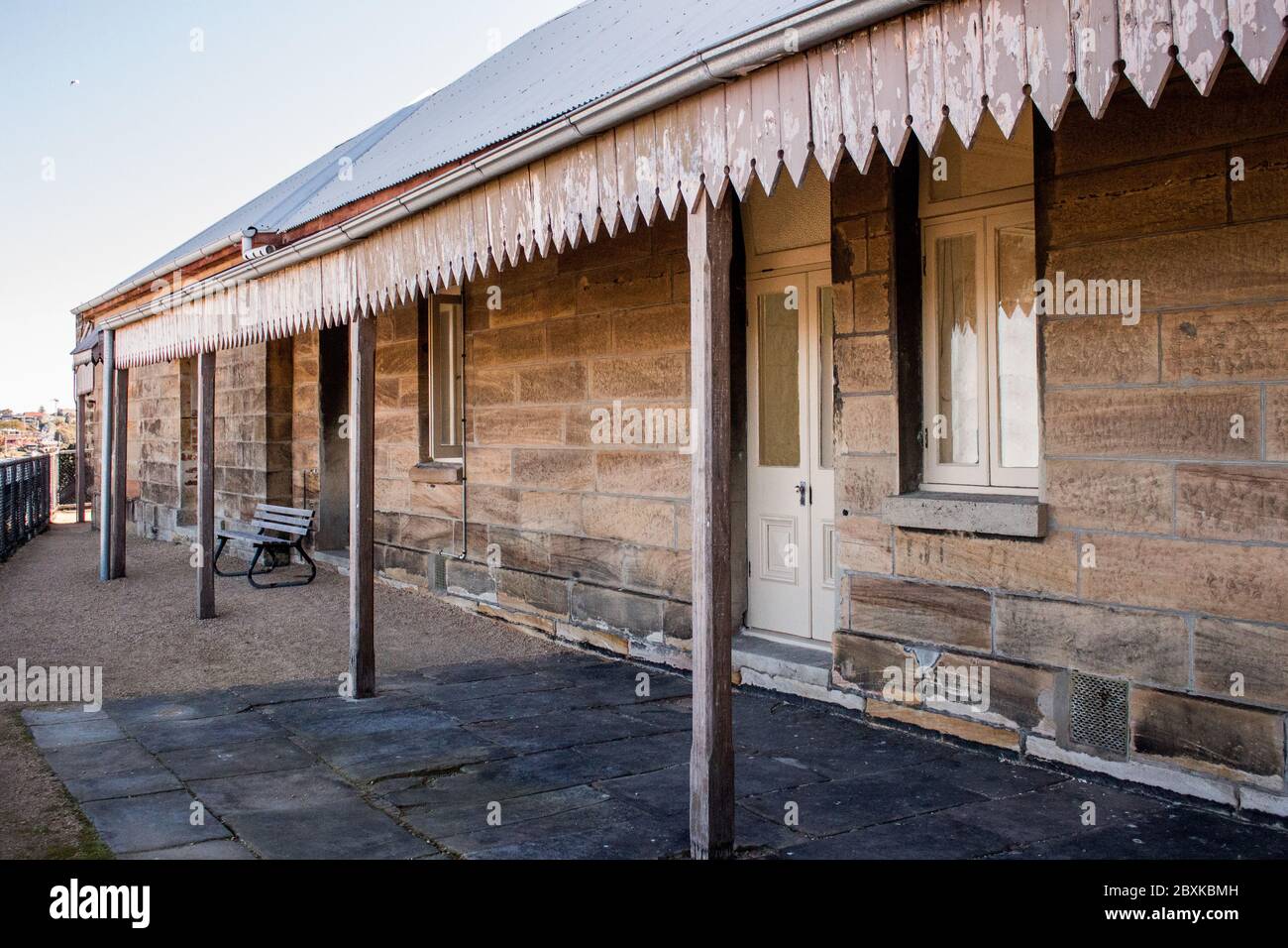 Historic Australian sandstone brick cottage exterior with verandah patio, corrugated iron roof Stock Photo