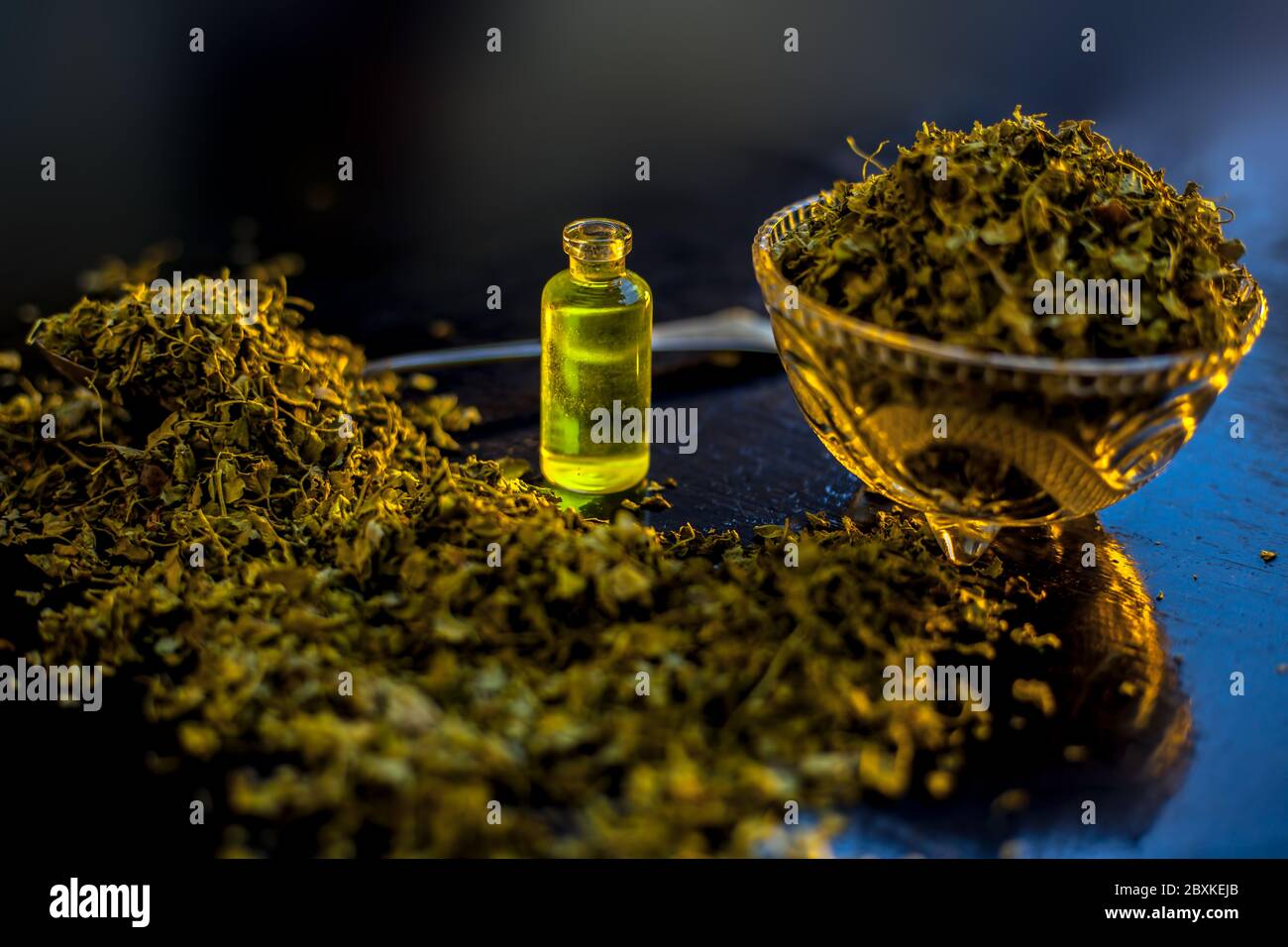 Essential extracted oil of Kasuri Methi or Dried Fenugreek Leaves in a small tiny bottle along with raw dried fenugreek leaves. Stock Photo