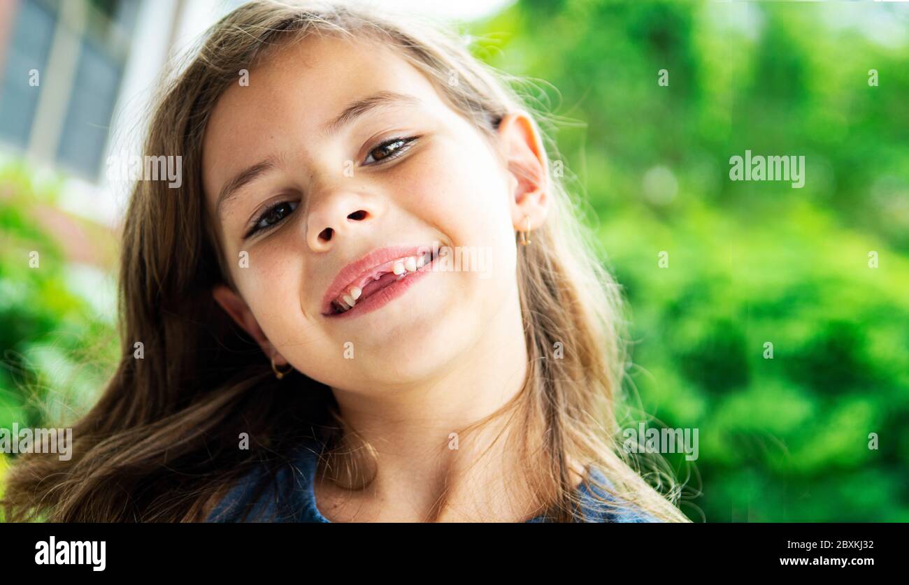 Seven year old girl outside on a sunny day smiling and looking into camera Stock Photo