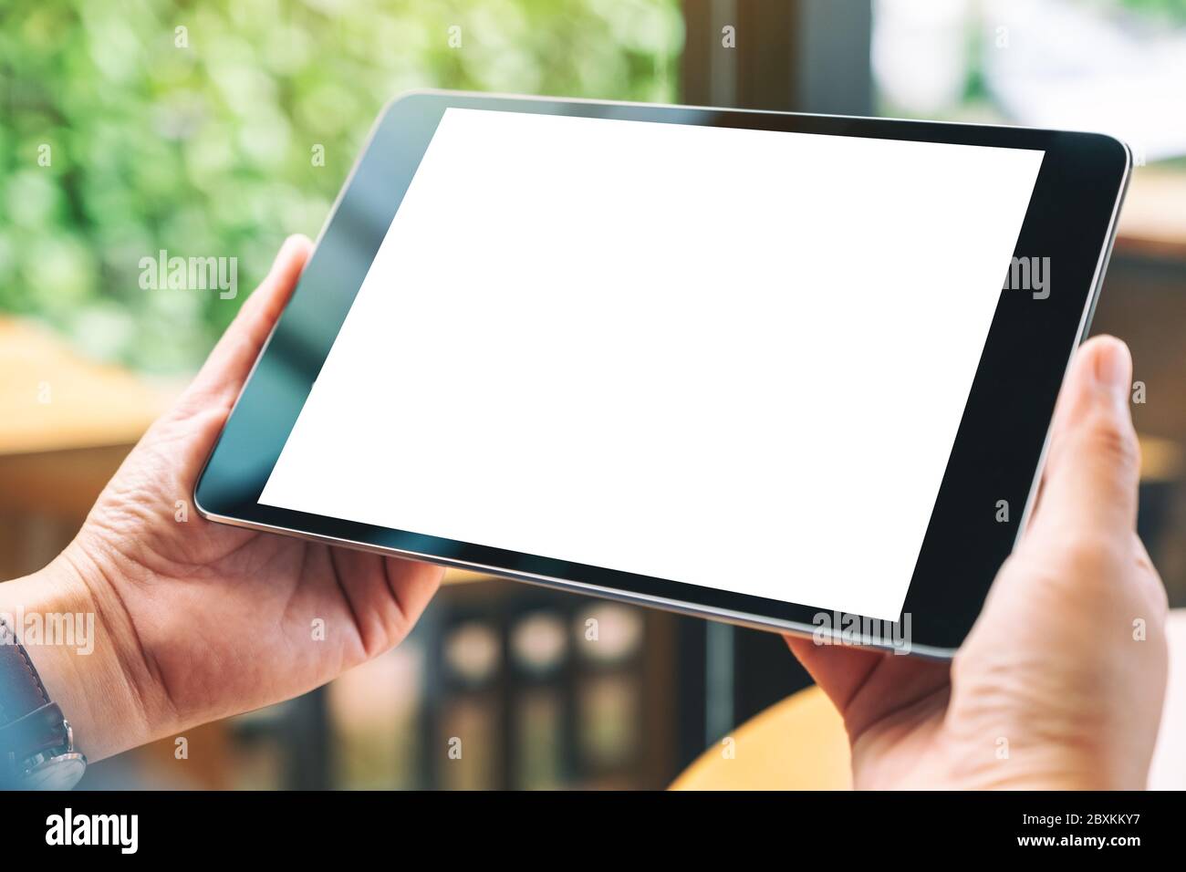 Mockup image of hands holding black tablet pc with blank white desktop ...
