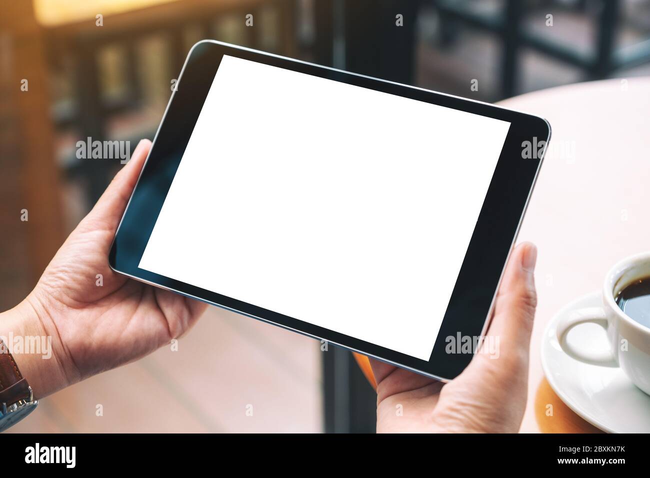 Mockup image of hands holding black tablet pc with blank white desktop ...