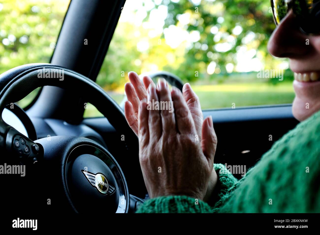 Clap for the NHS woman clapping in her car parked up on the roadside smiling Stock Photo