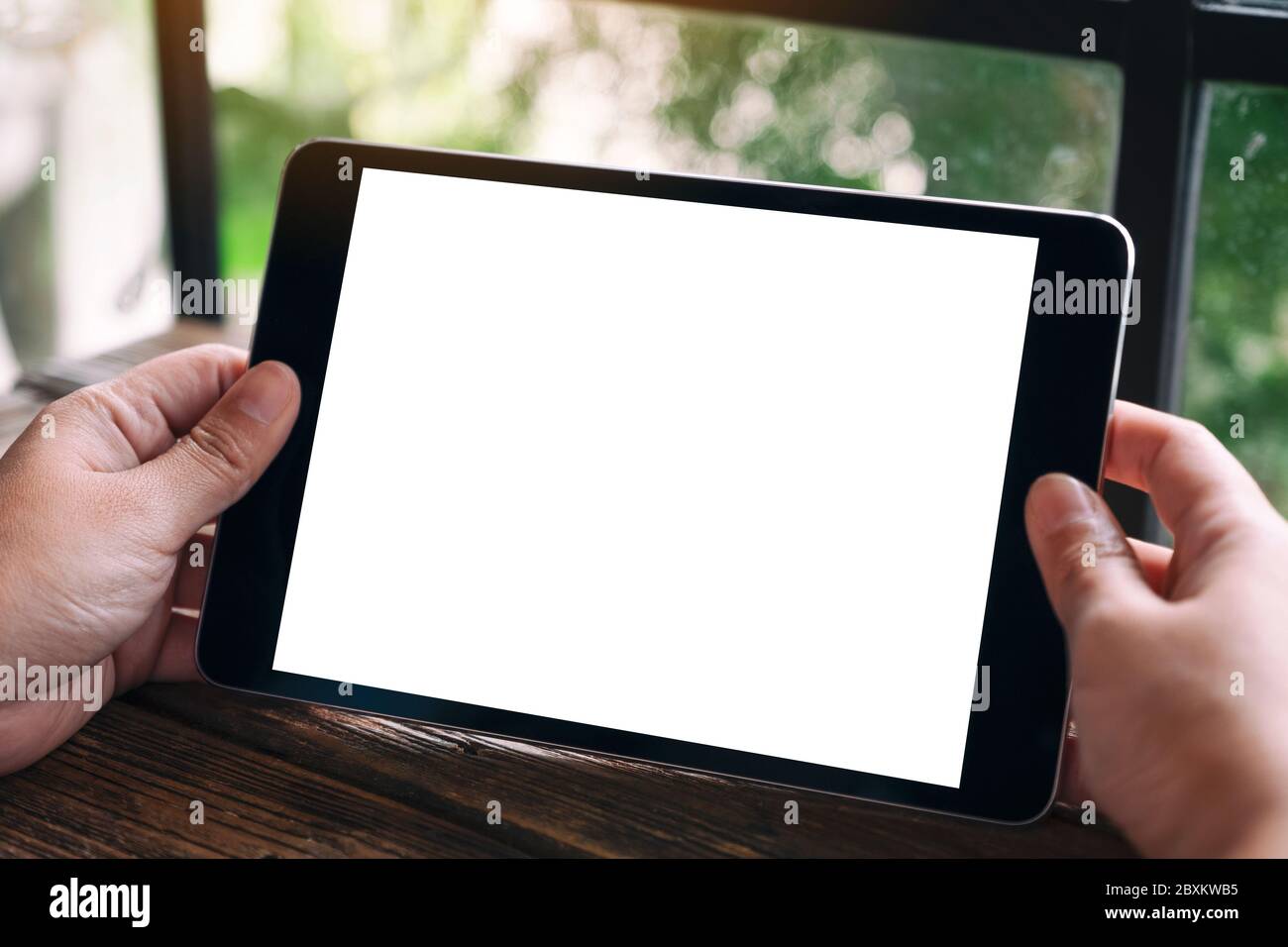 Mockup image of hands holding black tablet pc with blank white desktop ...