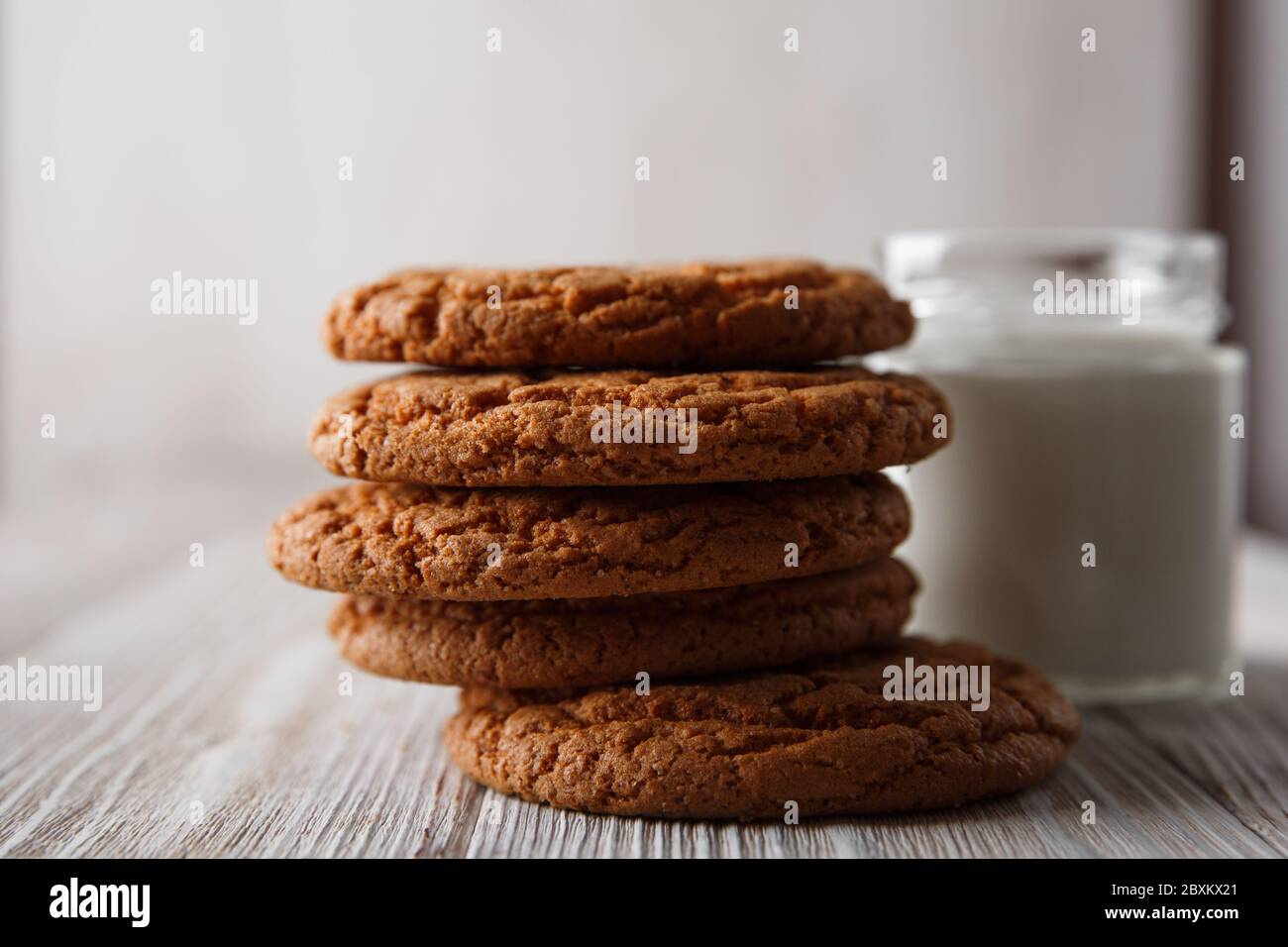 Tasty cookies and a glass of milk in a transparent glass on a rustic white background. Stock Photo