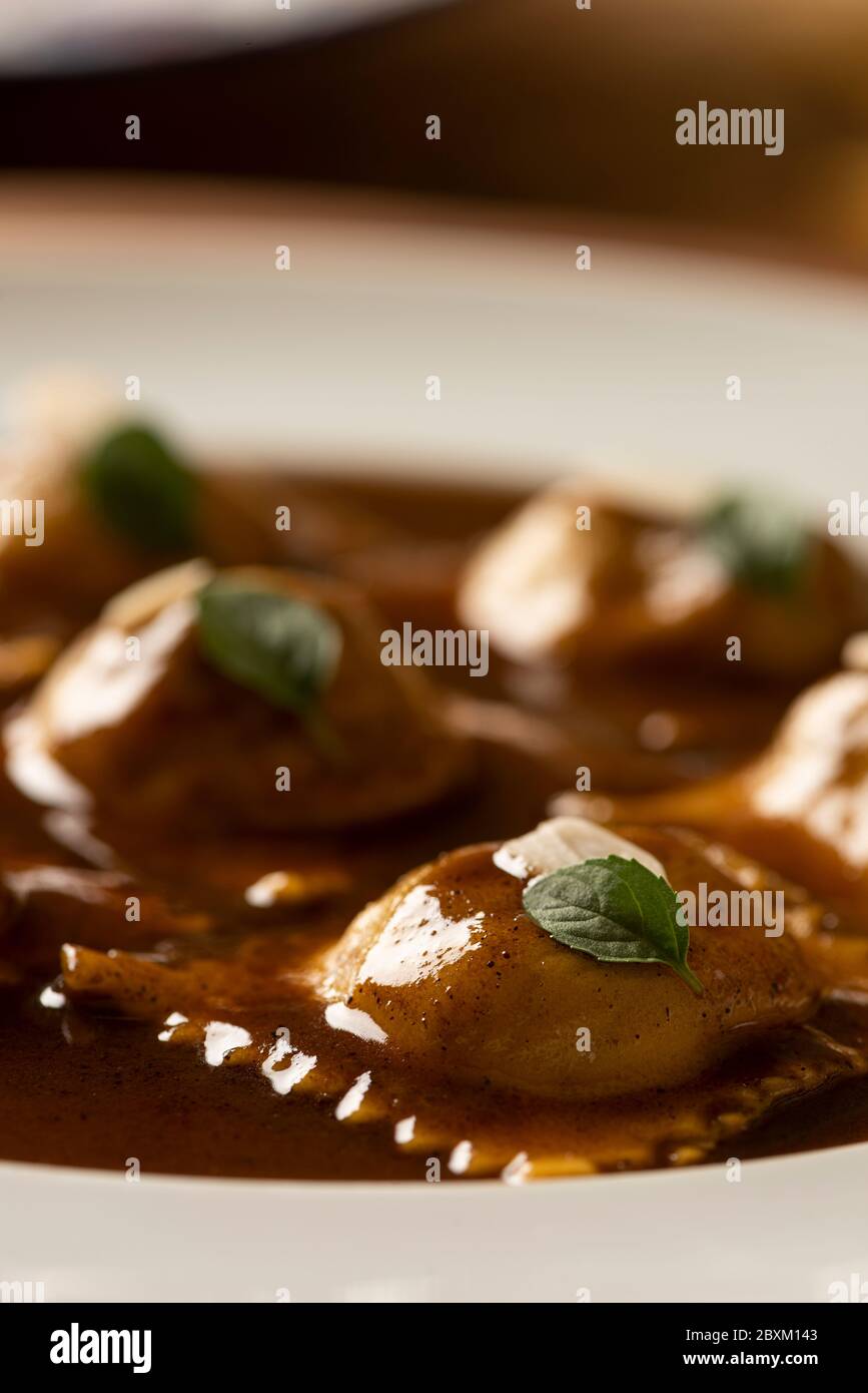 ravioli pasta on gravy, basil and almond slices on white plate - close up Stock Photo