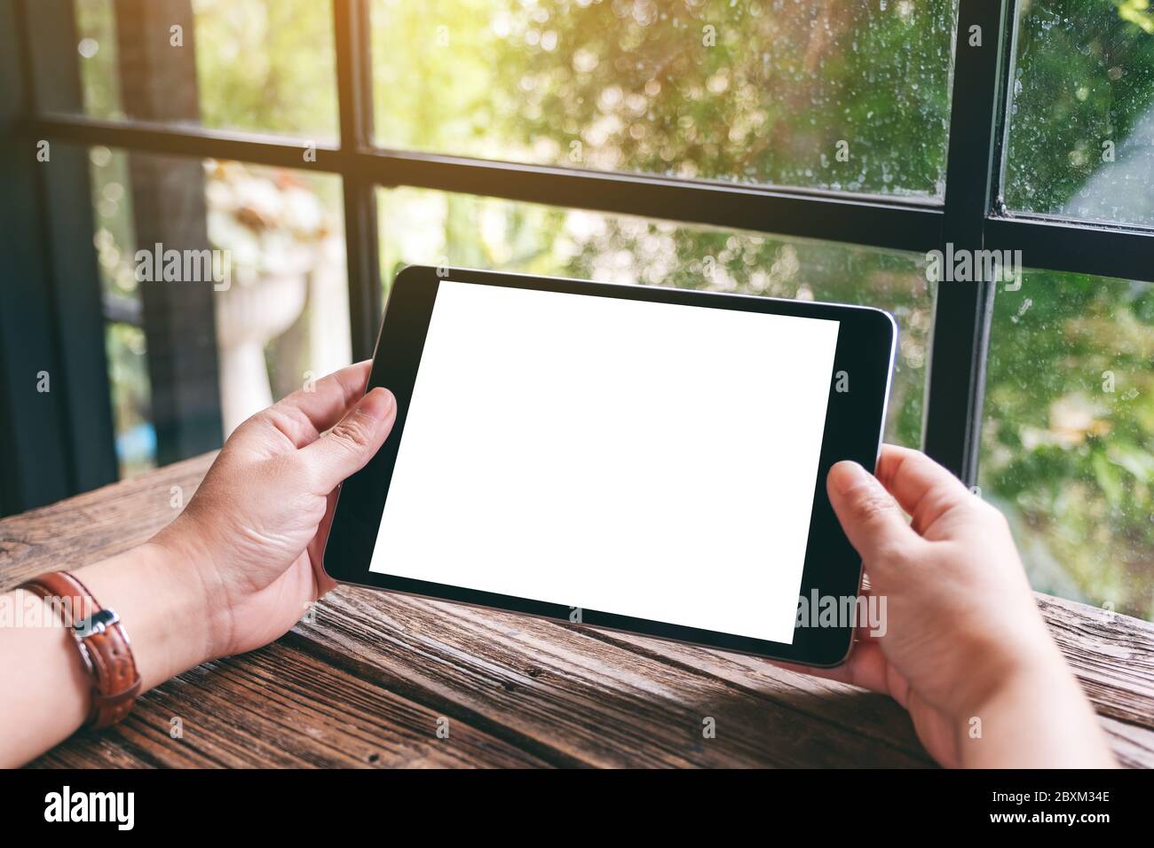Mockup image of hands holding black tablet pc with blank white desktop ...
