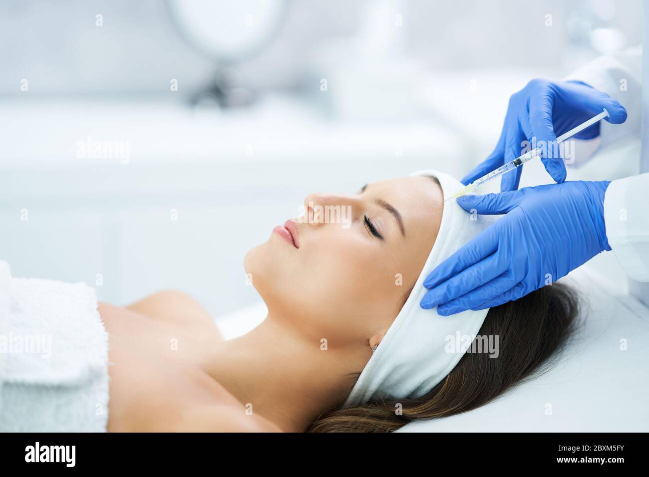 Beautiful young woman getting acid face treatment at beauty salon Stock