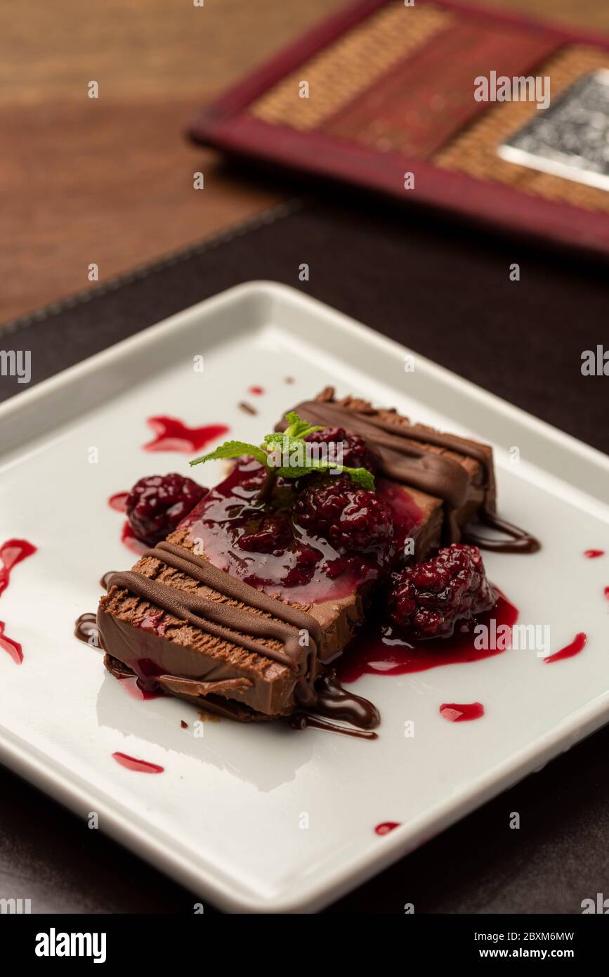chocolate terrine cake piece with raspberry syrup on white plate Stock