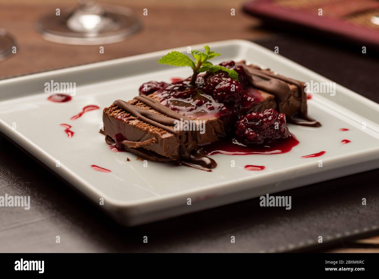 chocolate terrine cake piece with raspberry syrup on white plate Stock