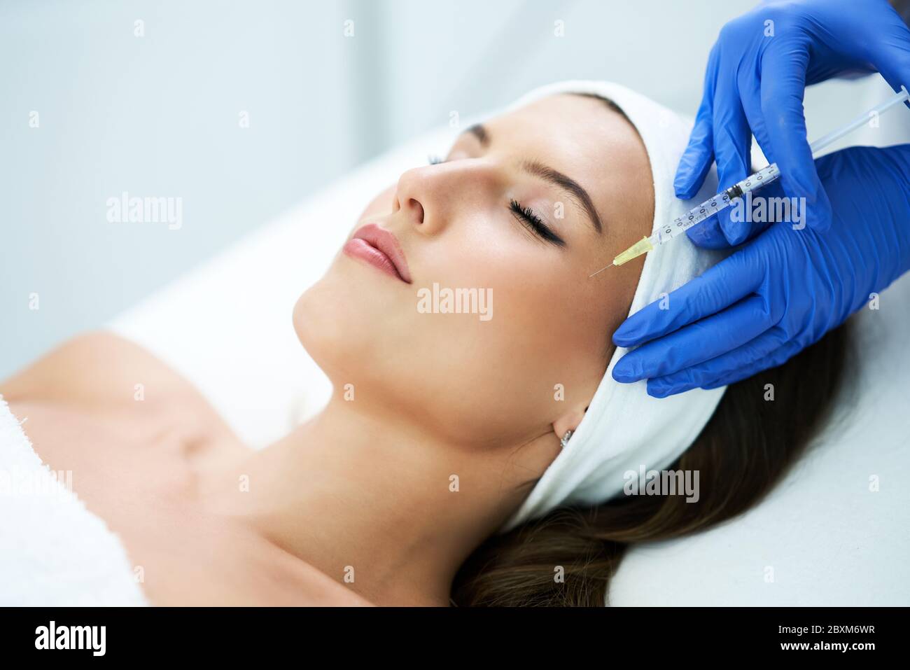 Beautiful young woman getting acid face treatment at beauty salon Stock