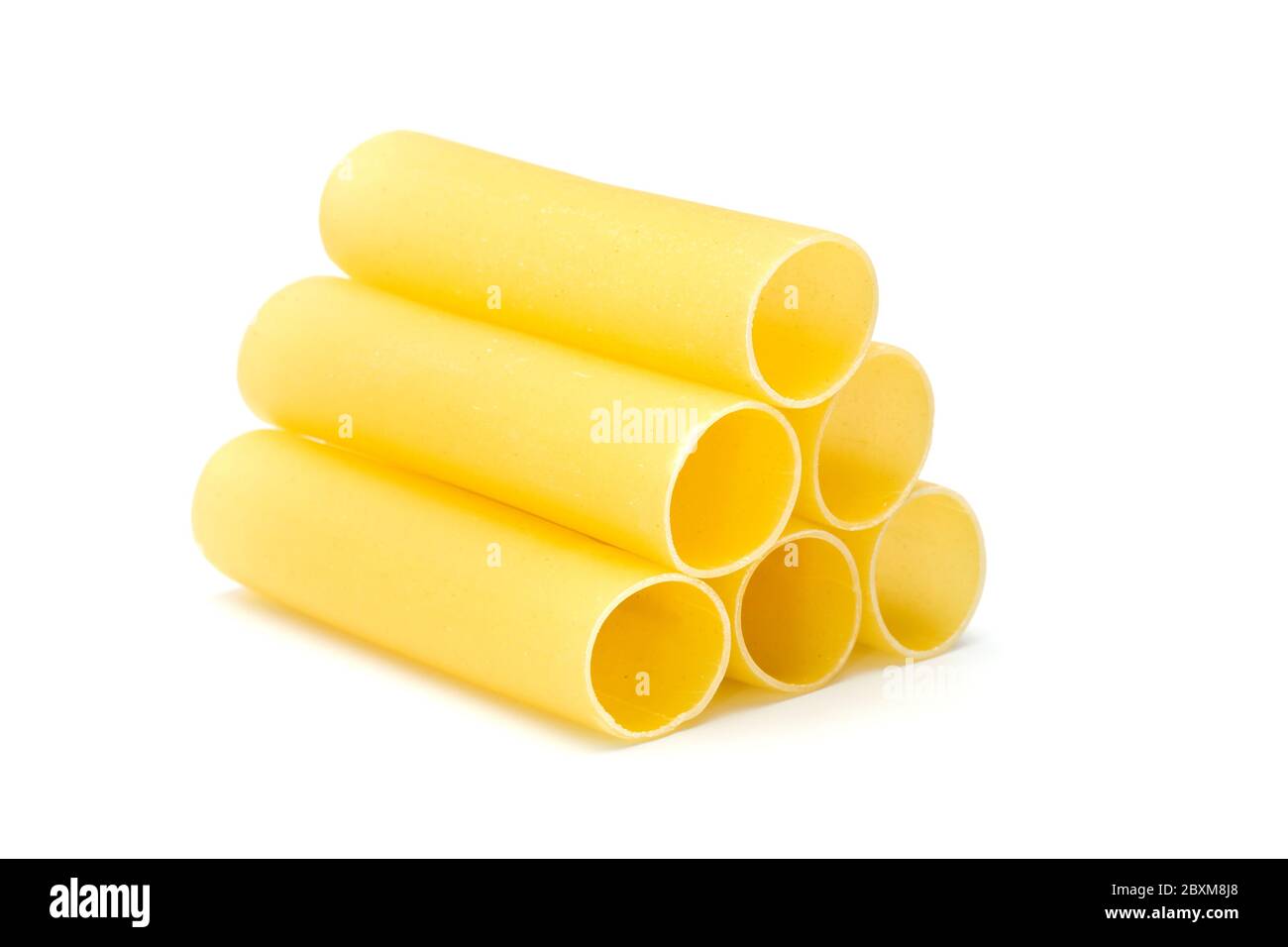 six raw canneloni pasta tubes stacked to pyramid, isolated on white Stock Photo