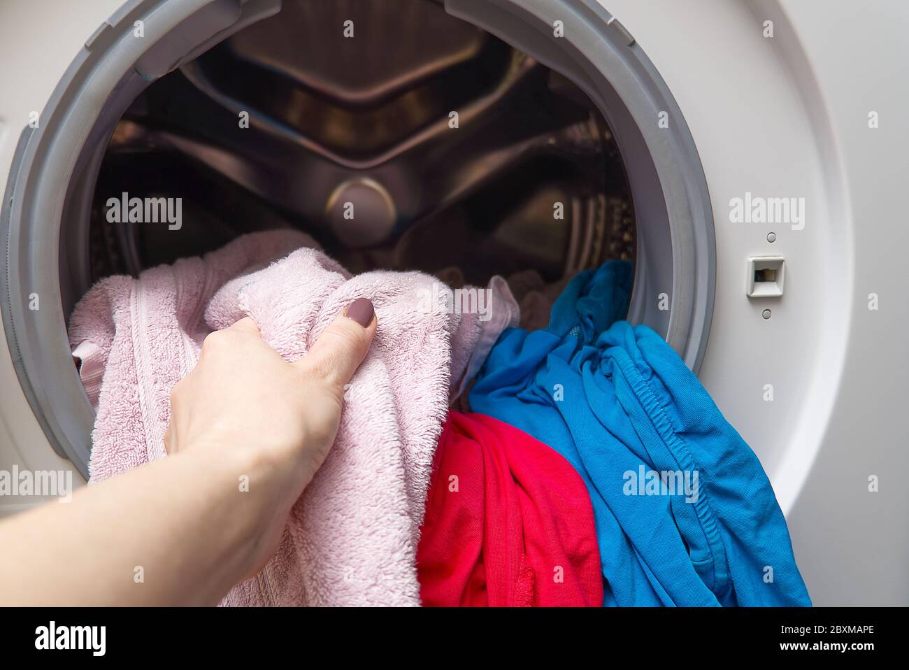 girl takes out the laundry from the washing machine. woman puts clothes ...