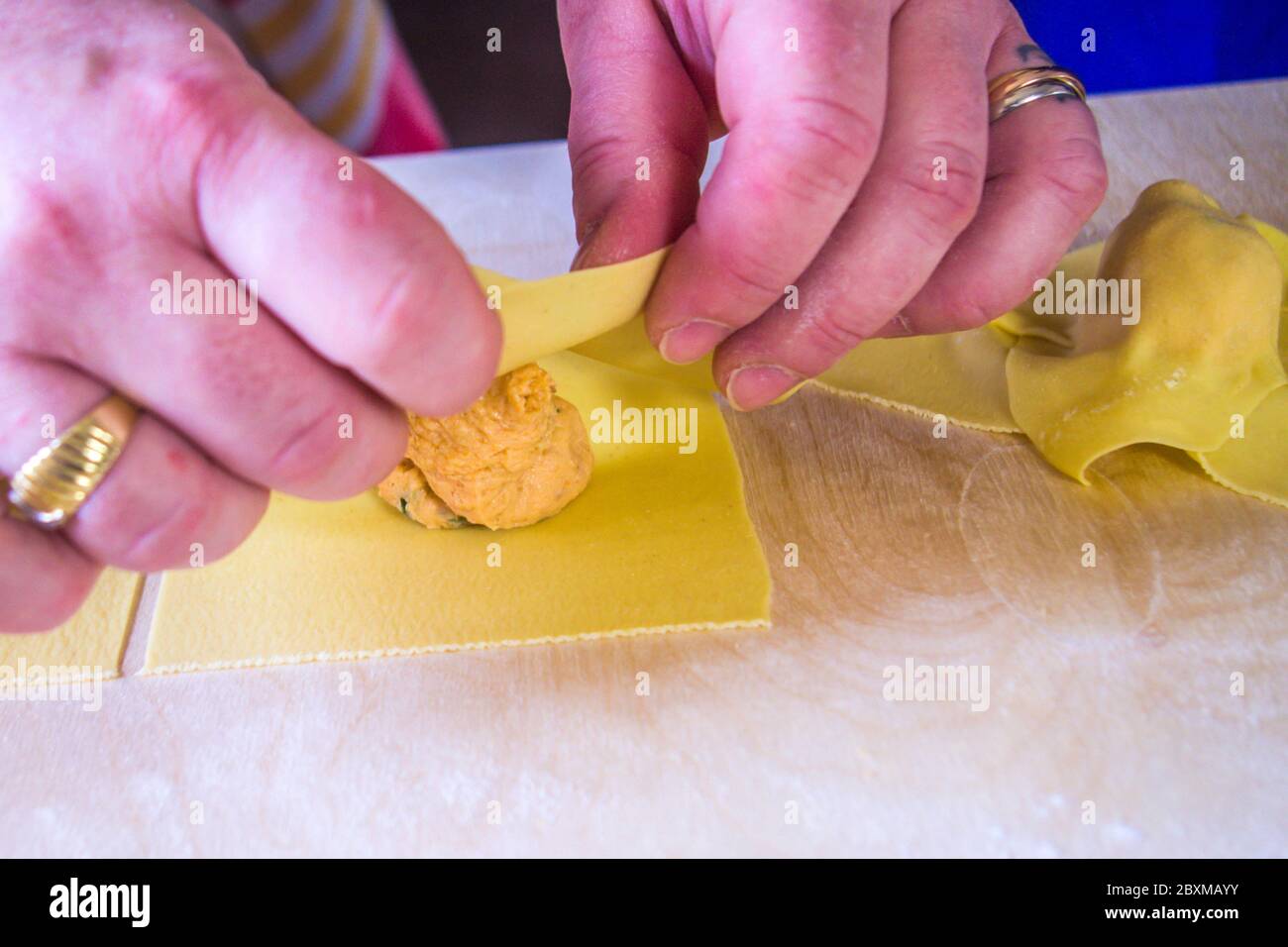 hand of the Italian housewife prepares egg pasta, ravioli and tortelli, stuffed with salmon stuffing, for the party lunch. Stock Photo