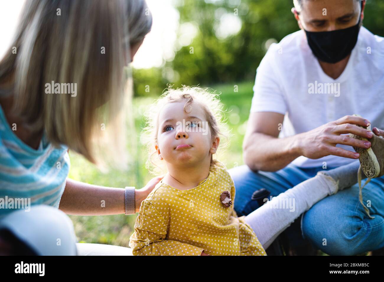 Family with small daughter on trip in nature, wearing face masks. Stock Photo