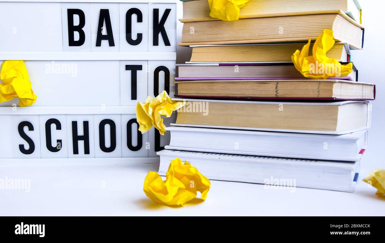 lightbox with BACK TO SCHOOL text and books on white background with crumpled yellow paper Stock Photo