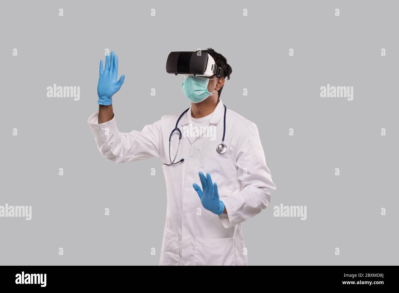 Doctor Wearing VR Glasses, Medical Mask and Gloves Hands to Sides Isolated. Indian Man Doctor Pointing in Virtual Reality Stock Photo