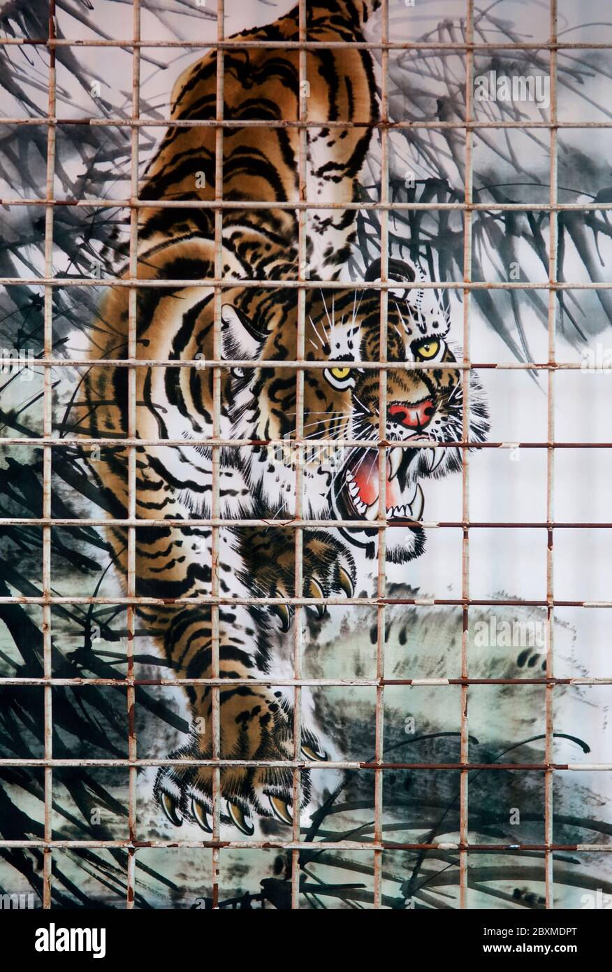 A Painting Of A Tiger On Fabric Displayed On An Outdoor Market Stall Viewed Through A Metal Fence Stock Photo