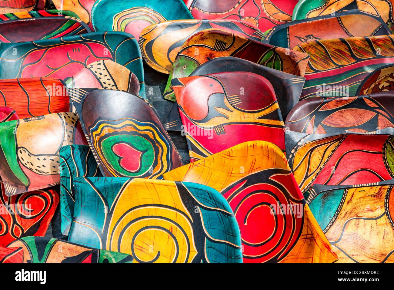 Rows of carved, hand painted wood bowls. Hand crafted souviner giftware, with colourful tribal designs, at a market in South Africa. Stock Photo