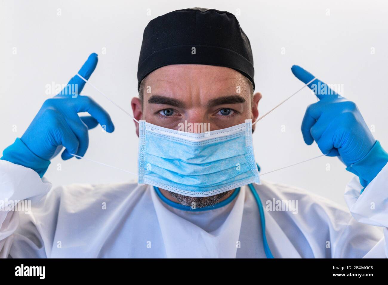 Doctor getting dressed with biological hazard suit and face surgical mask during coronavirus