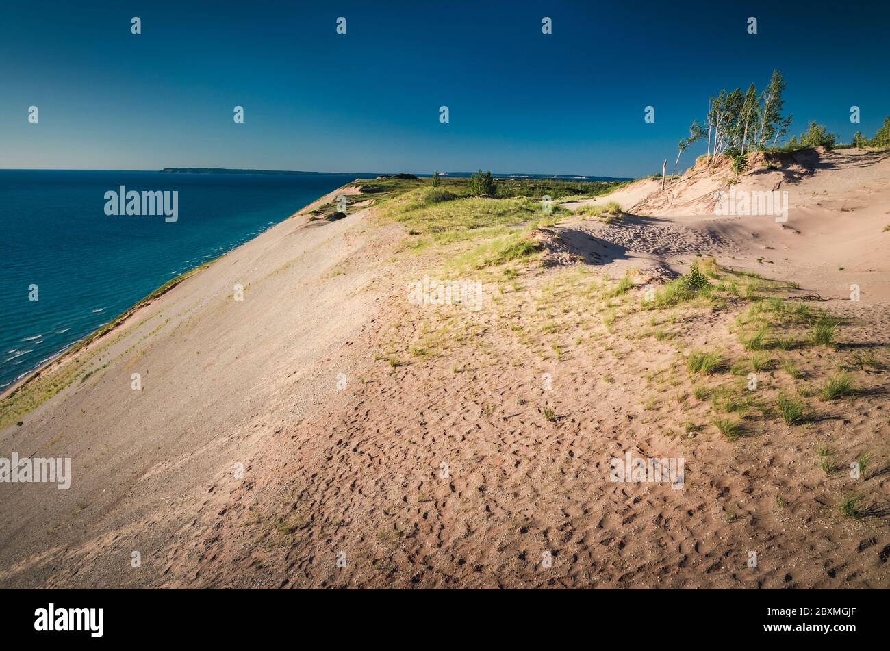 Sleeping Bear Dunes are perched, sitting atop the already high glacial moraines. Waves cut away the bases of the bluffs, exposing a continuous supply Stock Photo