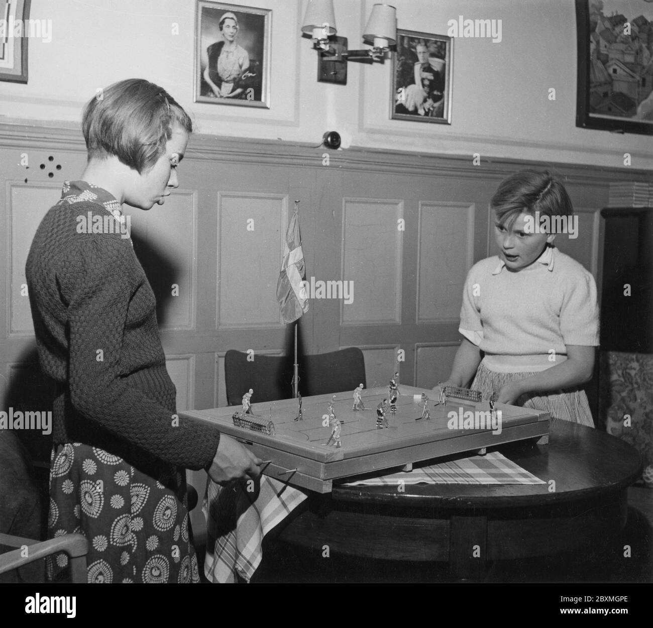 In the 1950s. Two girls are playing the Ice Hockey game Puck. Manufactured by Swedish company Aristospel. At this time patented and alone on the market to sell the game. The players maneuver the figures on the board by moving and twisting them around and like real hockeyplayers move the puck around to try to score a goal. 1950s Stock Photo