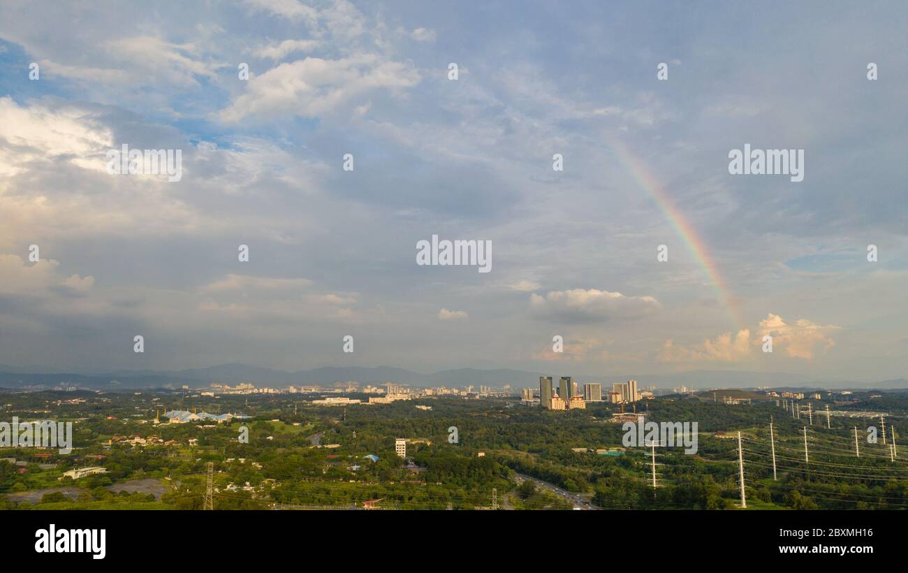 Aerial view of suburban landscape of Kuala Lumpur, Malaysia with visible rainbow and cloudy sky. Stock Photo