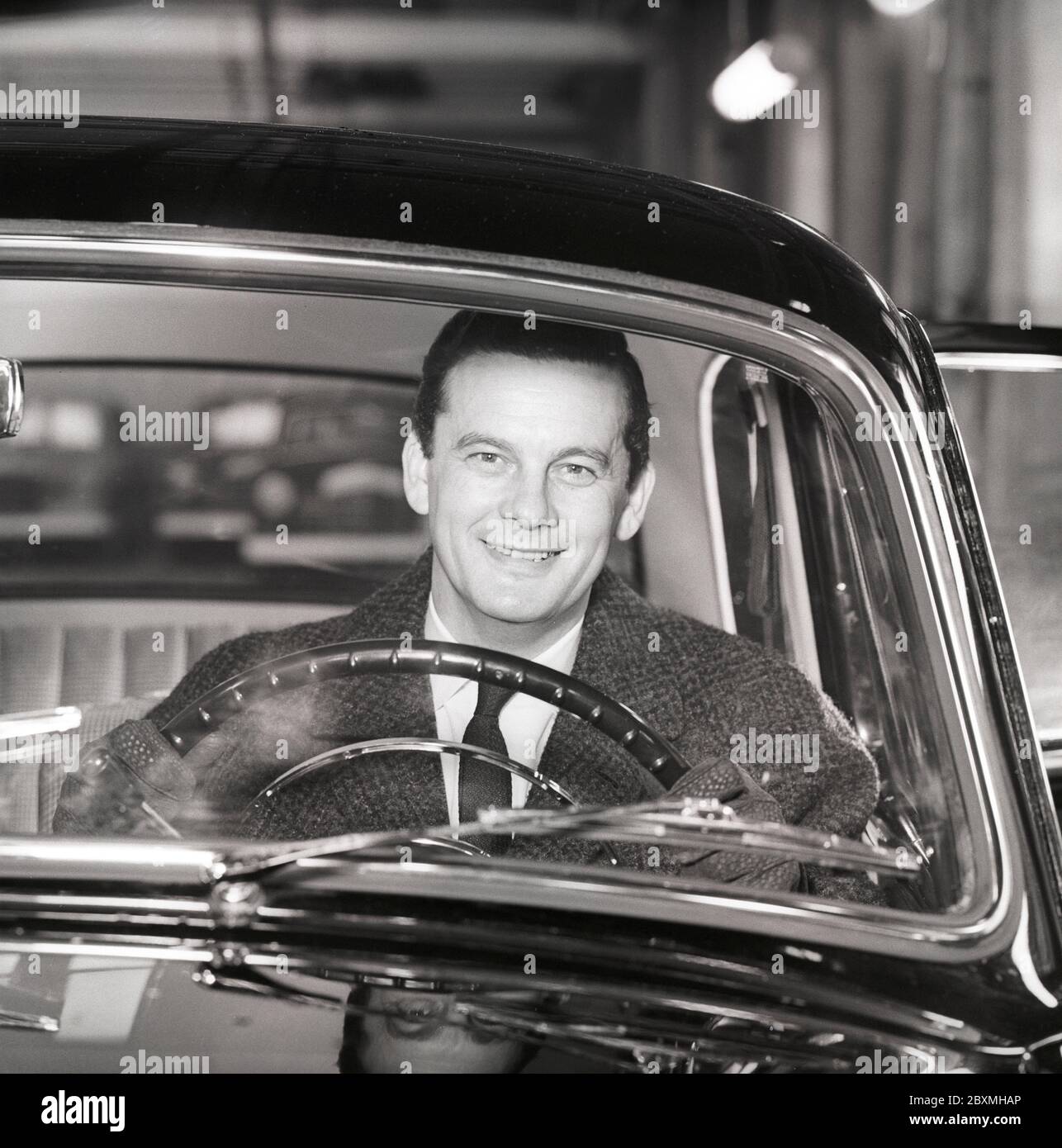 Driving in the 1960s. A man behind the steering wheel in his car looks happy. Sweden 1960. Kristoffersson ref CS93-10 Stock Photo