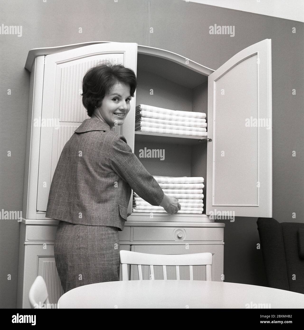 In the 1960s. A woman is putting in linen in a nice carpented cupboard by swedish designer Carl Malmsten.  Sweden 1960. Kristoffersson Ref CS12-1 Stock Photo