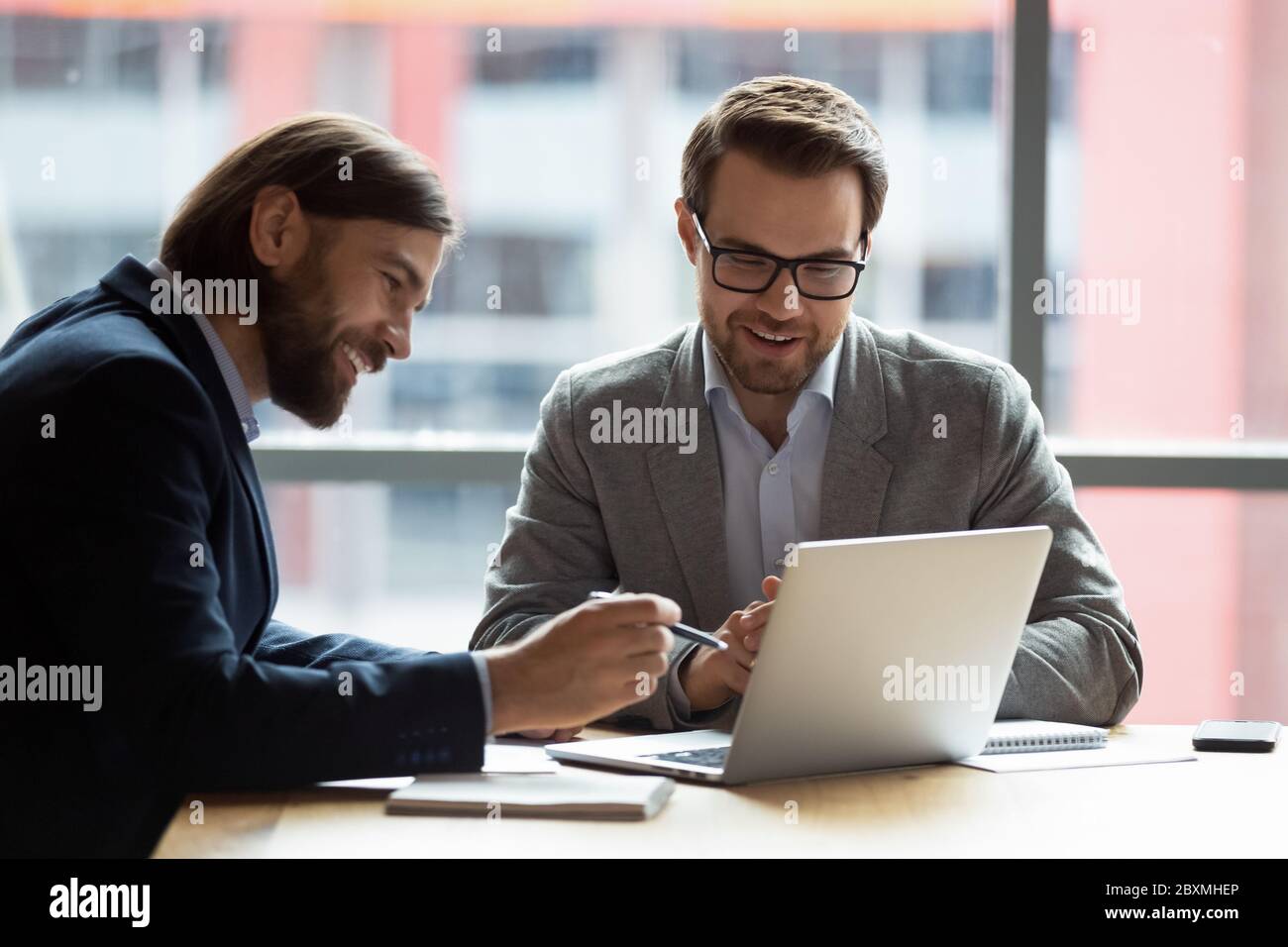 Teammates positive businessmen using laptop learn new corporate app Stock Photo