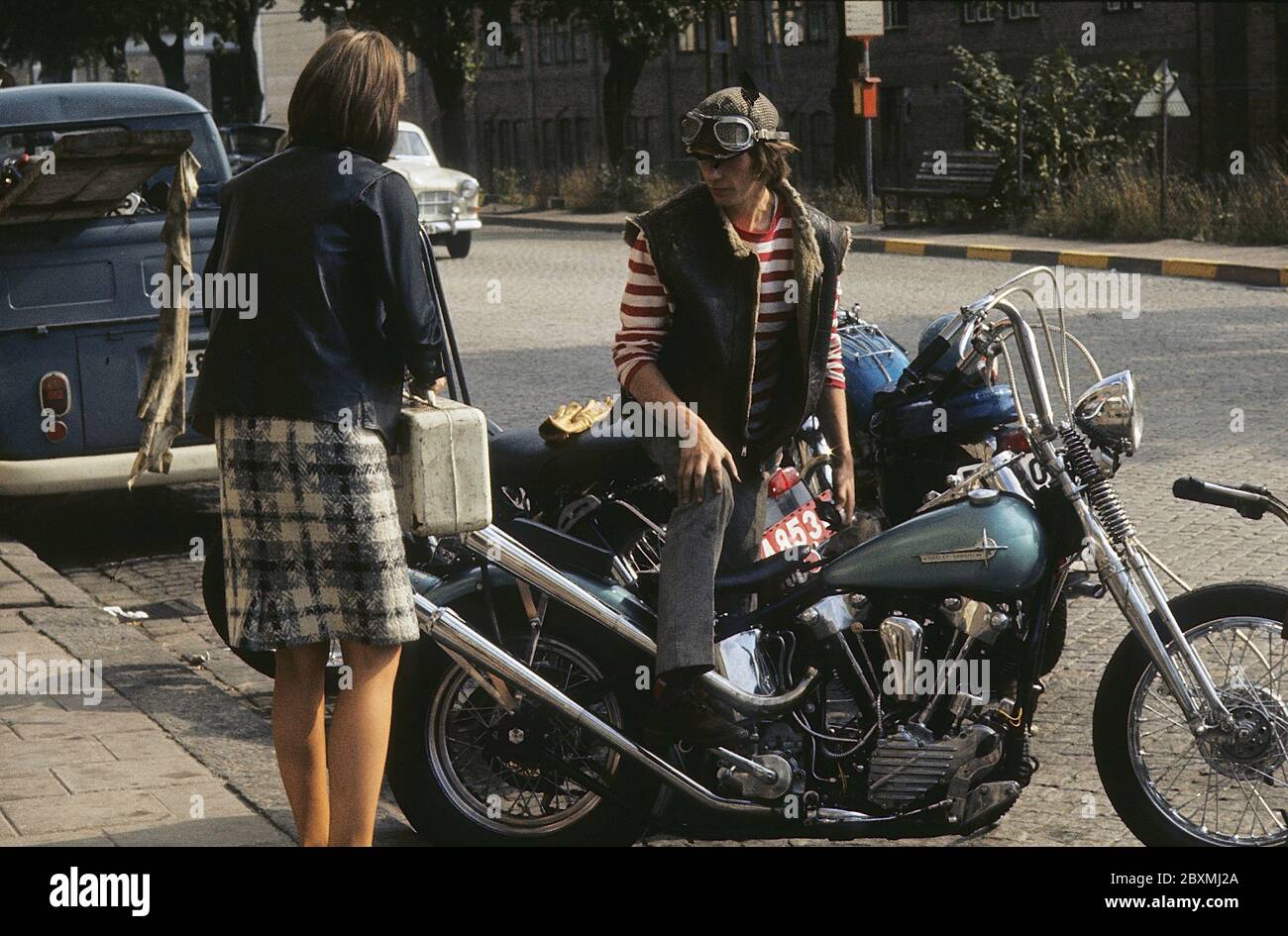 In the 1960s. A young man on his Harley Davidson motorcycle. The law of  wearing a safety helmet is not yet in force and at this time it was popular  to wear