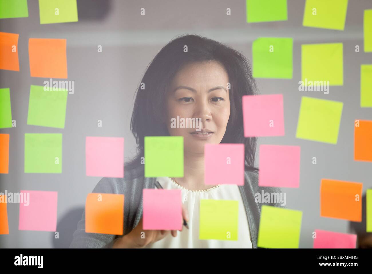Mature asian coach makes presentation for staff using sticky notes Stock Photo