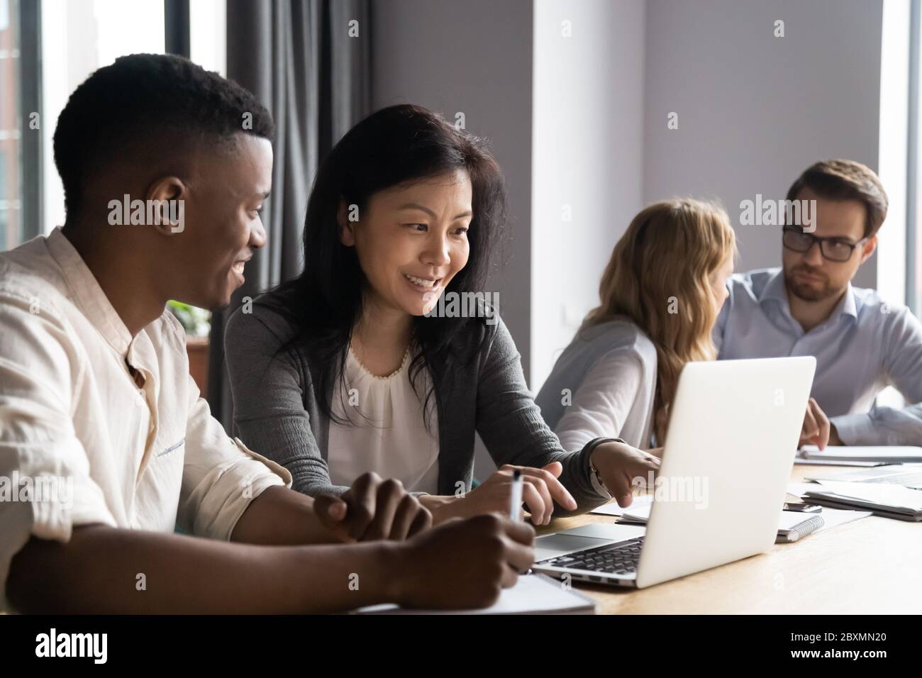 Multiethnic younger older affiliates working on task using laptop together Stock Photo