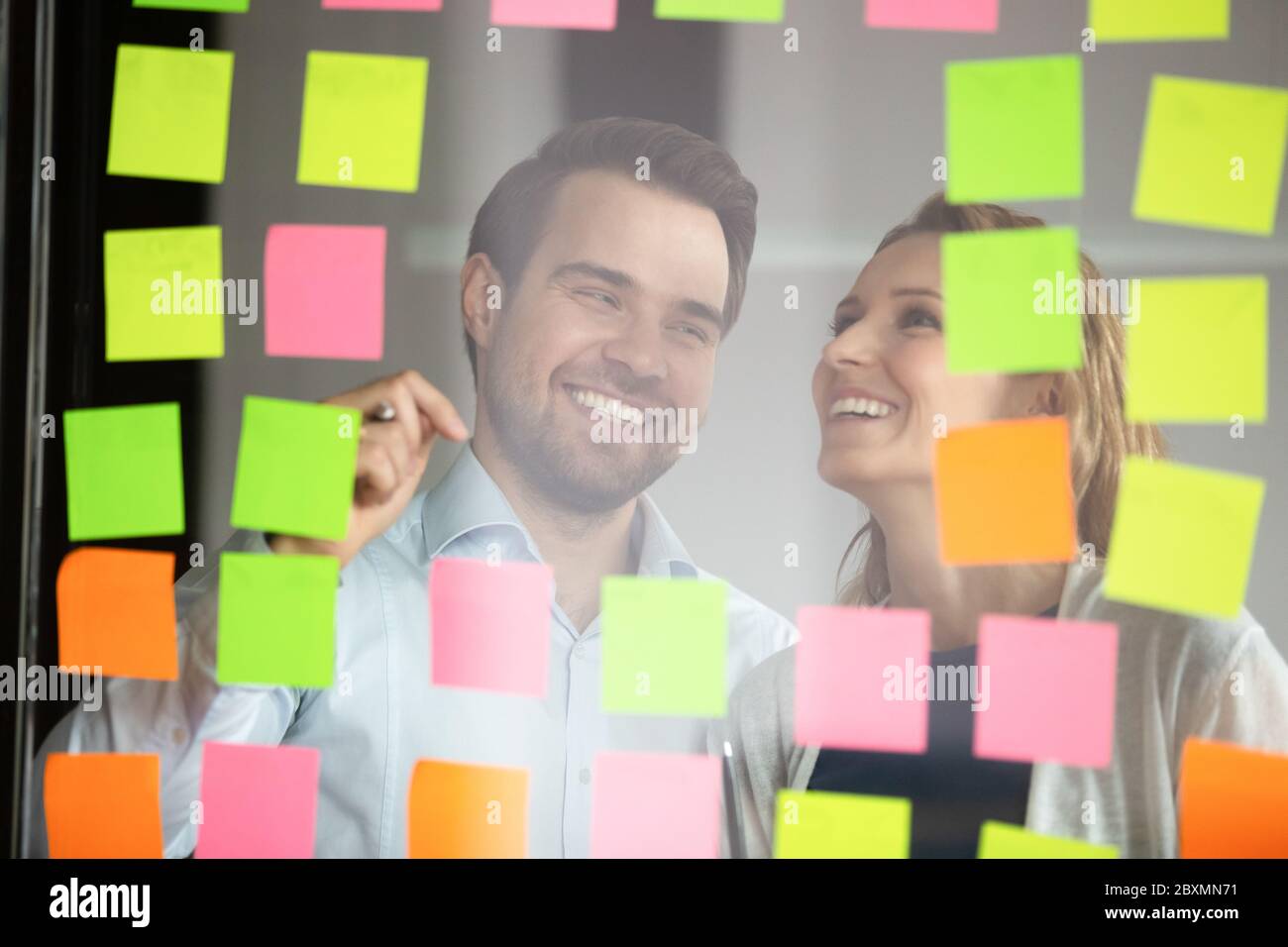 Colleagues attaching sticky notes working on to-do list Stock Photo