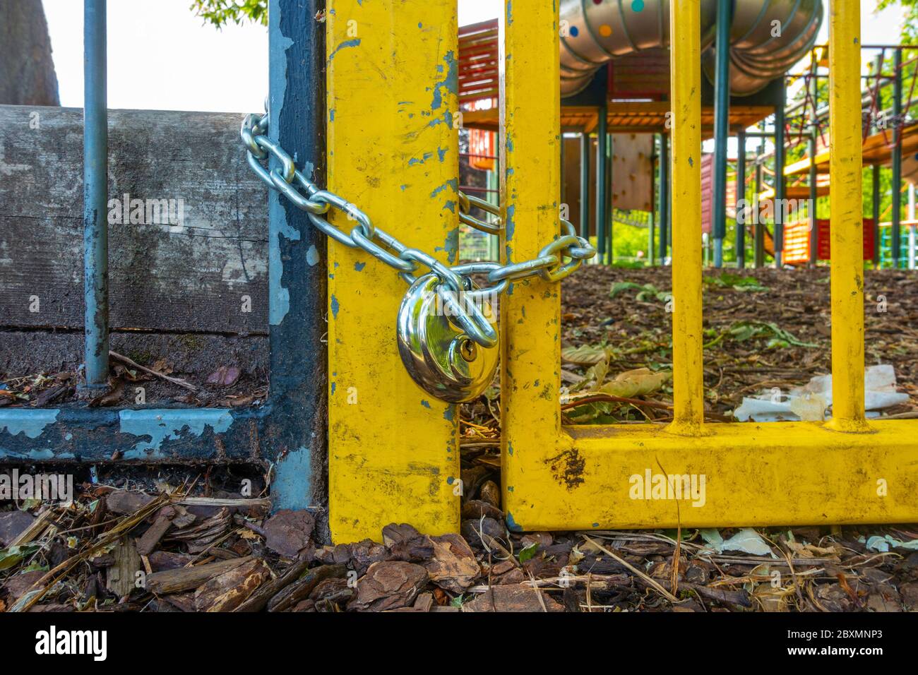 The gate at the entrance to a children's playground is shut with a chain and padlock die to coronavirus pandemic social distancing rules. Stock Photo