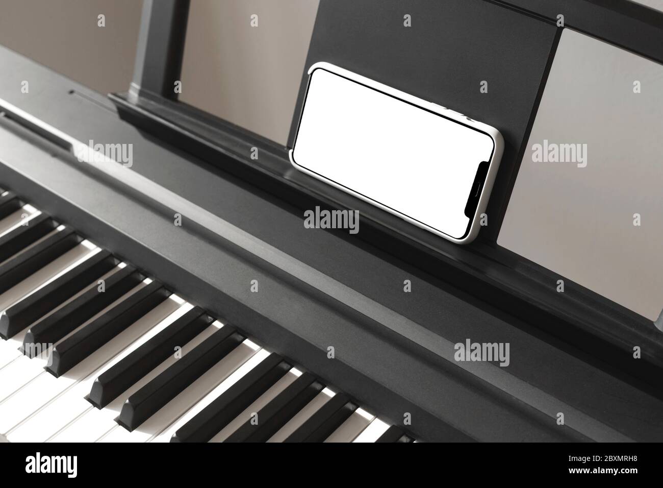 Isolated smartphone screen in female hands near the piano. Stock Photo
