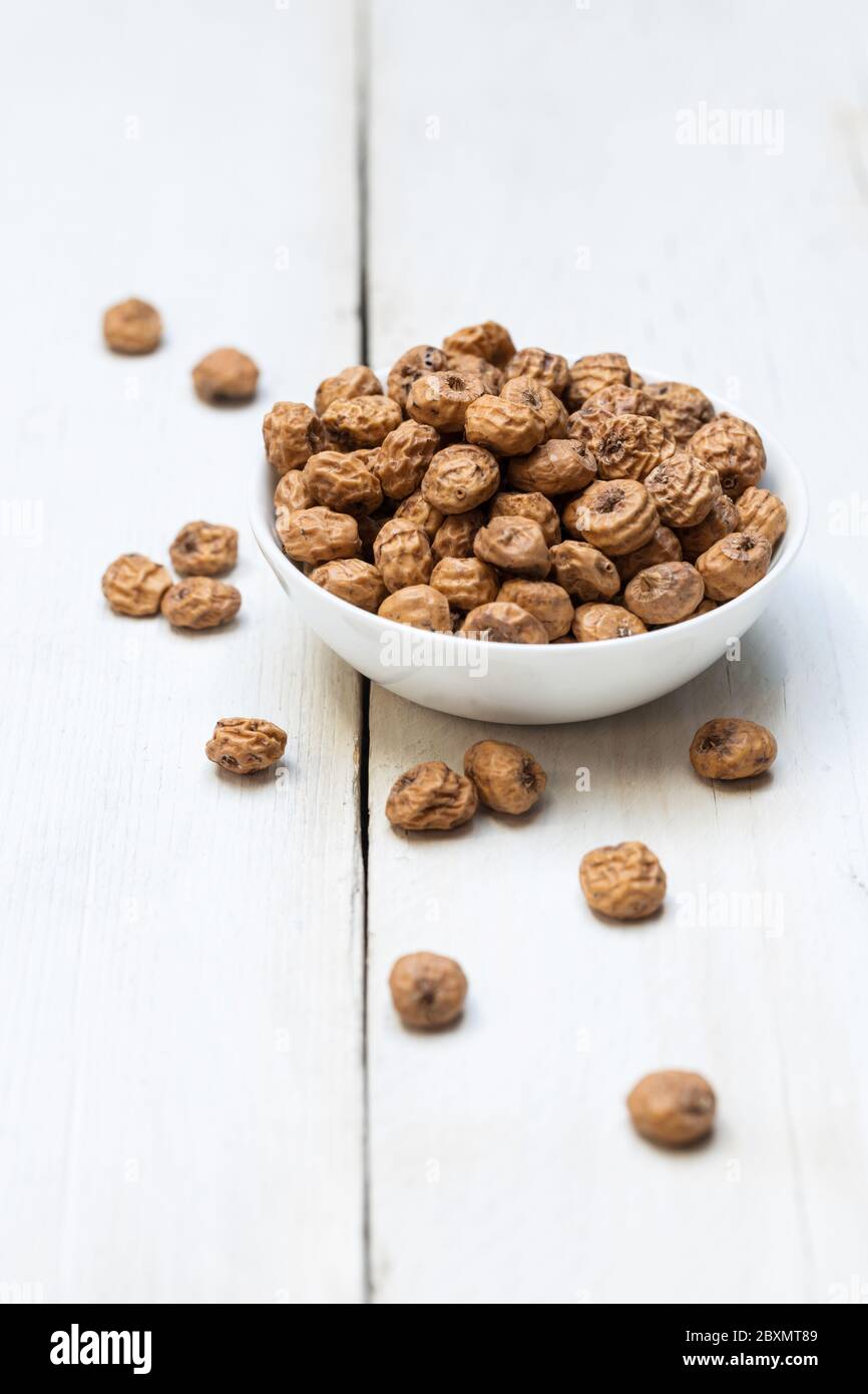 Tigernuts in a bowl on a wooden surface. Stock Photo