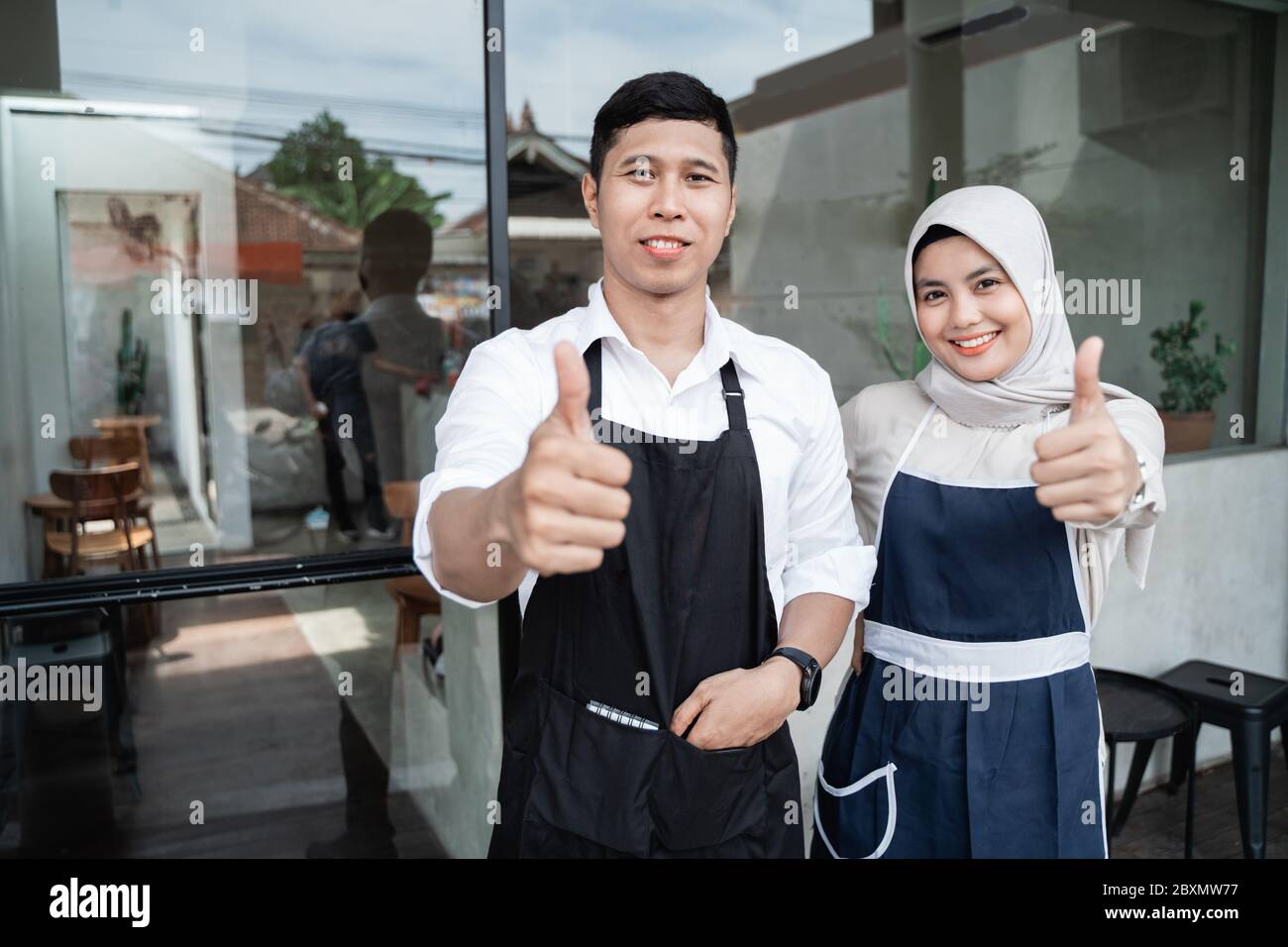 two waitress standing with thumbs up in front coffee shop for opening ...