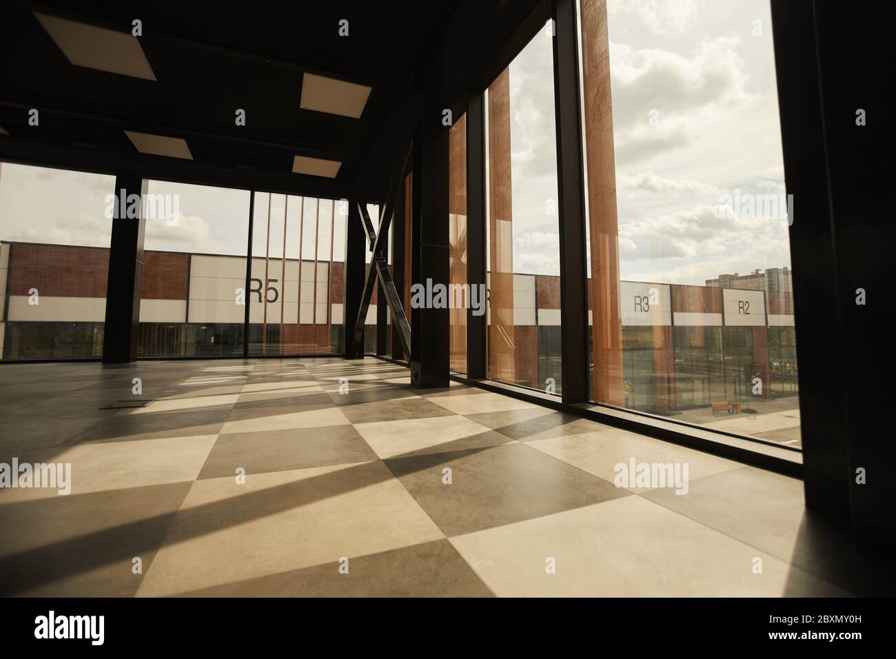 Background image of empty office building interior with floor to ceiling windows lit by sunlight, copy space Stock Photo