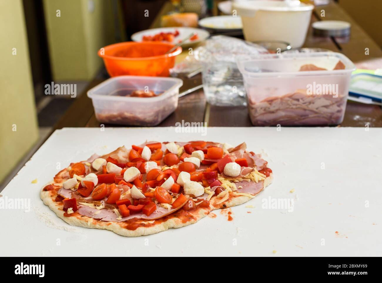 Making of homemade Italian pizza in fireplace brick oven. Making of pizza and adding different ingredients before baking it in outside fireplace. Ingr Stock Photo