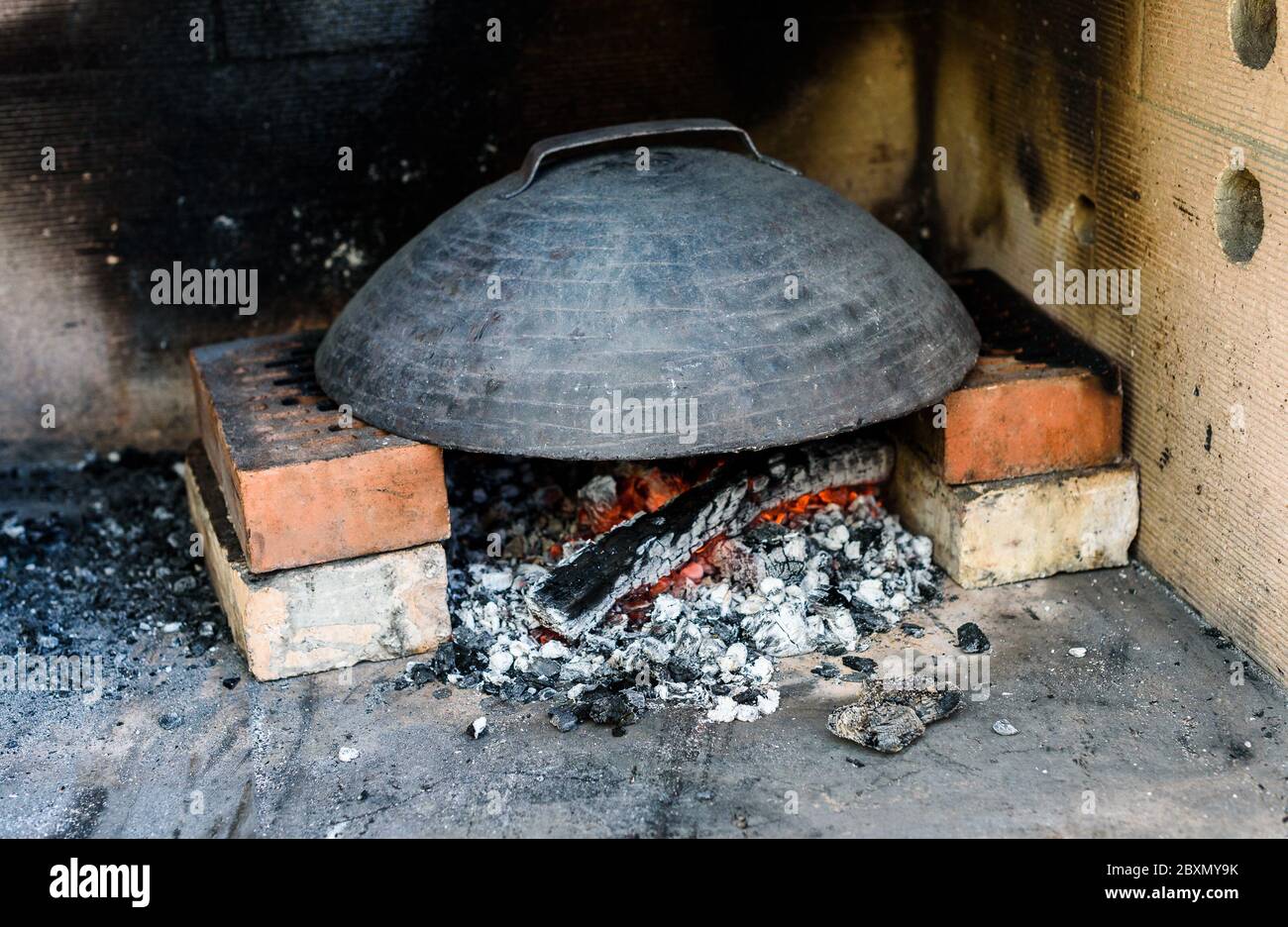 Making of homemade Italian pizza in fireplace brick oven. Making of traditional pizza in stone brick fireplace with fire wood and coals.Heating up a m Stock Photo