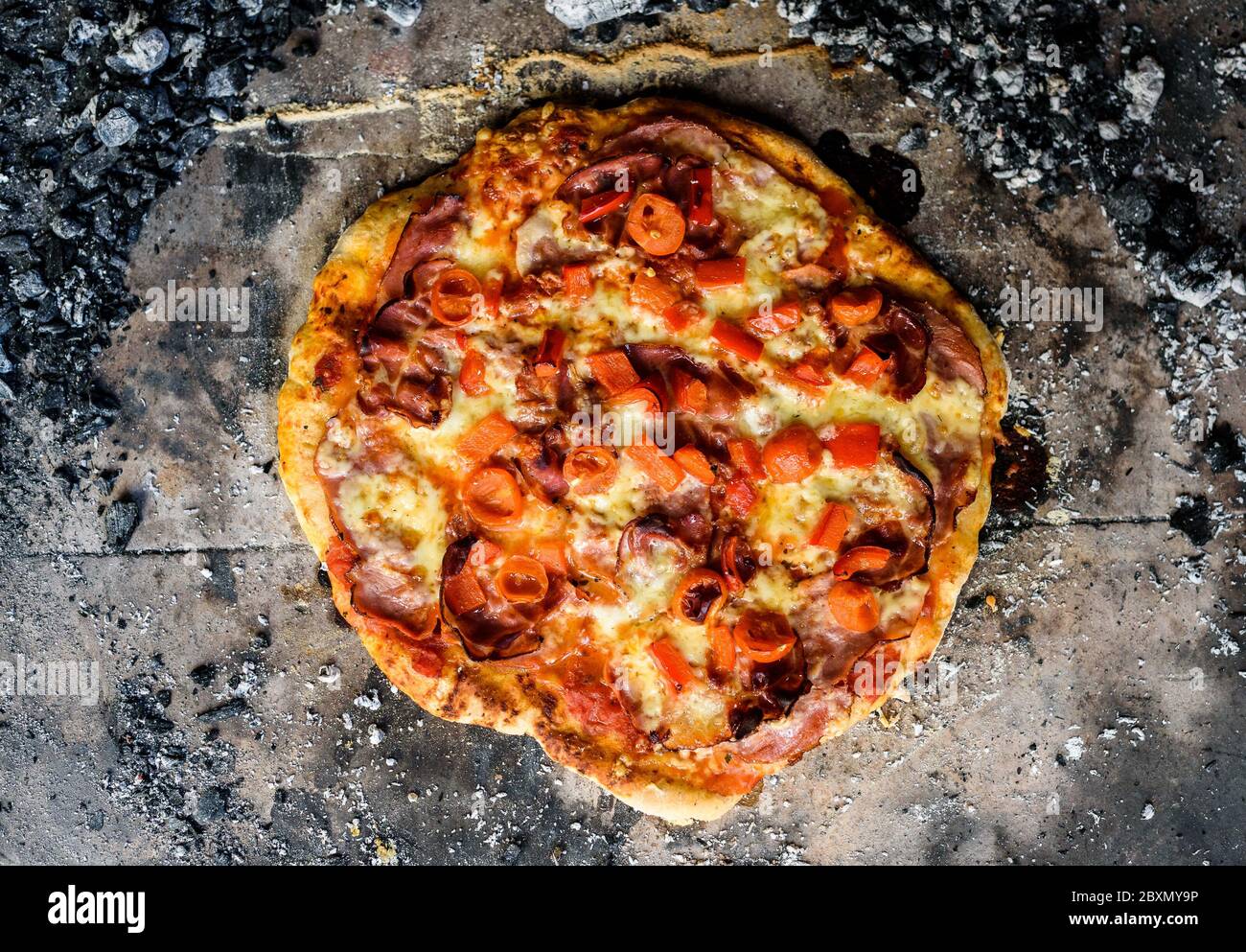 Making of homemade Italian pizza in fireplace brick oven. Making of traditional pizza in stone brick fireplace with fire wood and coals. Finished tast Stock Photo