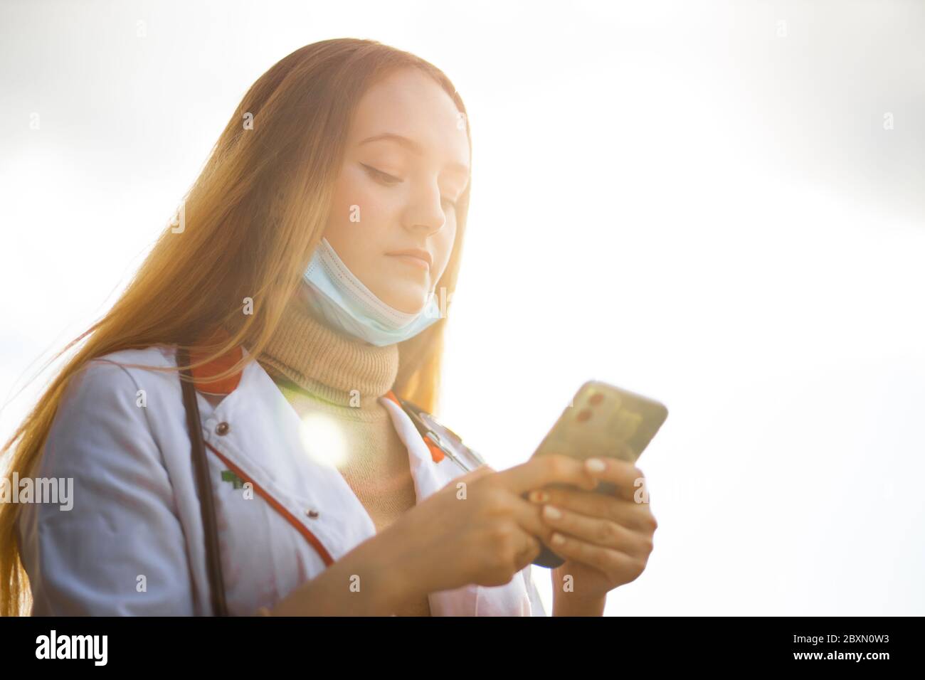Young female doctor texting using smartphone during break Stock Photo