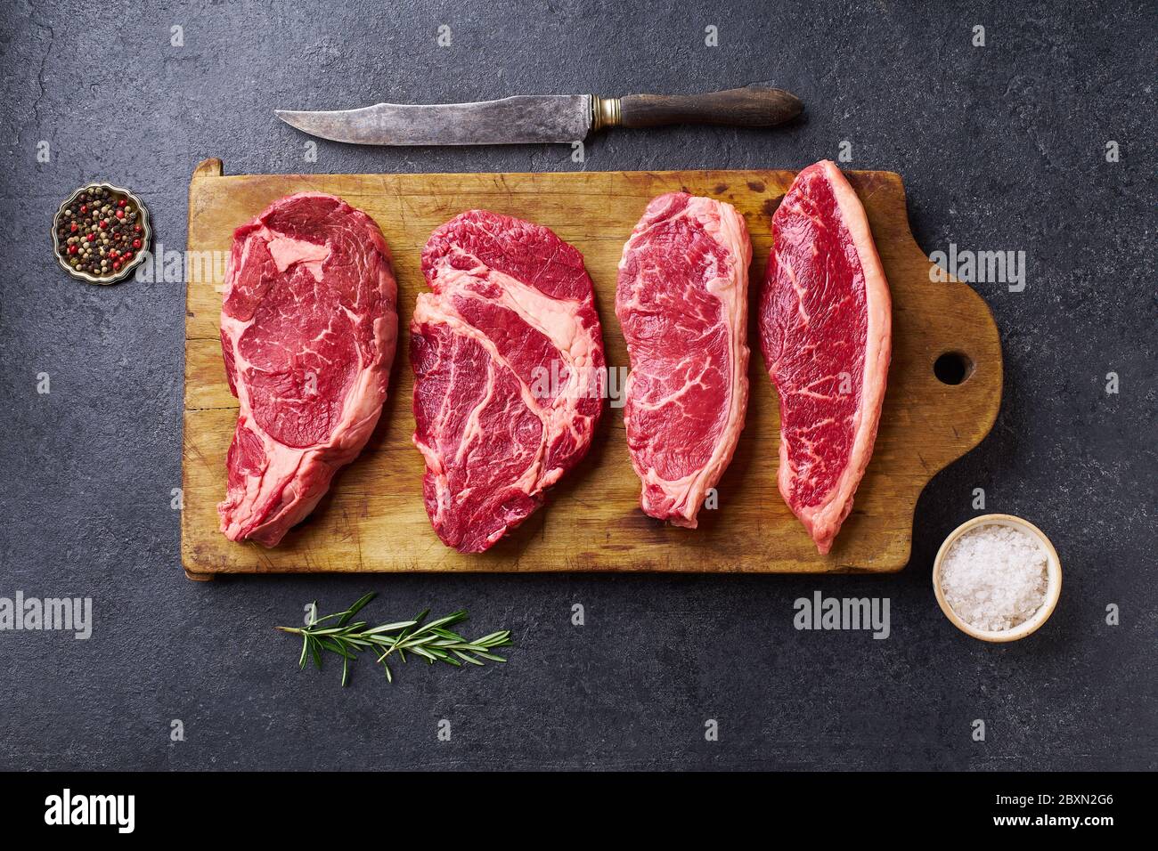 Variety of fresh Black Angus Prime raw beef steakes: ribeye, striploin, chuck roll and picanha on wooden cutiing board Stock Photo