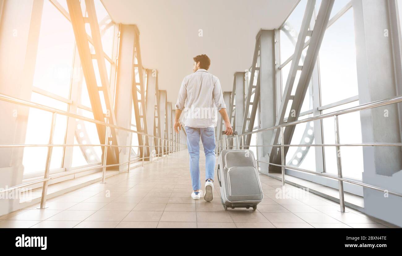 Rear View Of Young Man Walking With Luggage In Airport Terminal Stock ...