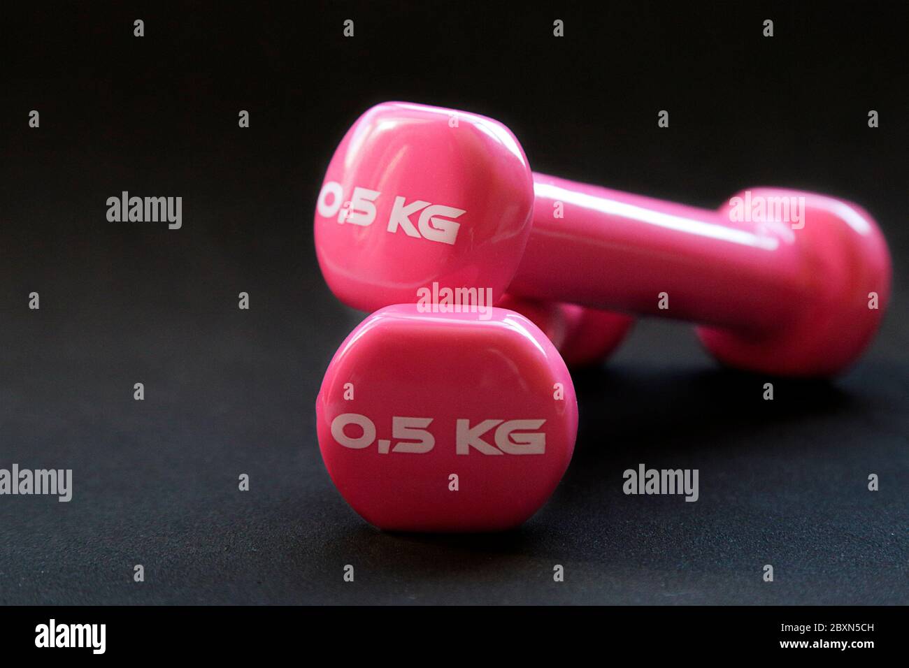 Pink dumbbells for fitness weighing 0.5 kg over a black background Stock Photo